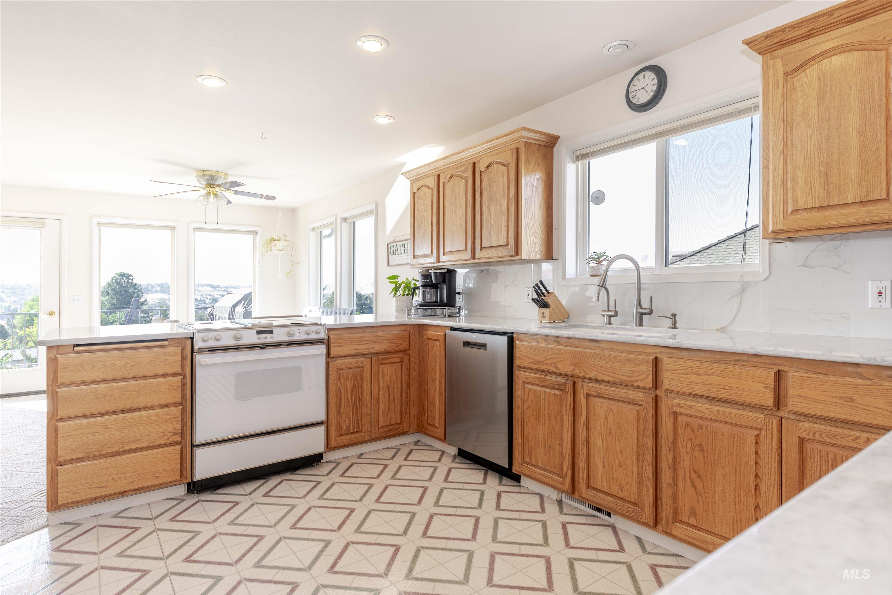 Kitchen featuring electric stove, a peninsula, dishwasher, ceiling fan, and tasteful backsplash