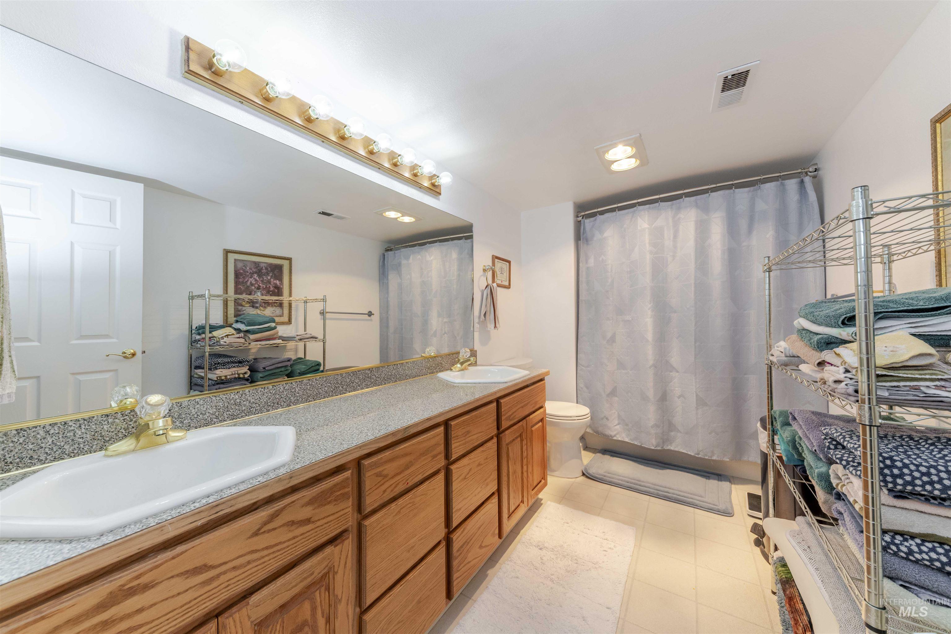 Full bathroom with double vanity, a shower with curtain, light tile patterned flooring, and recessed lighting