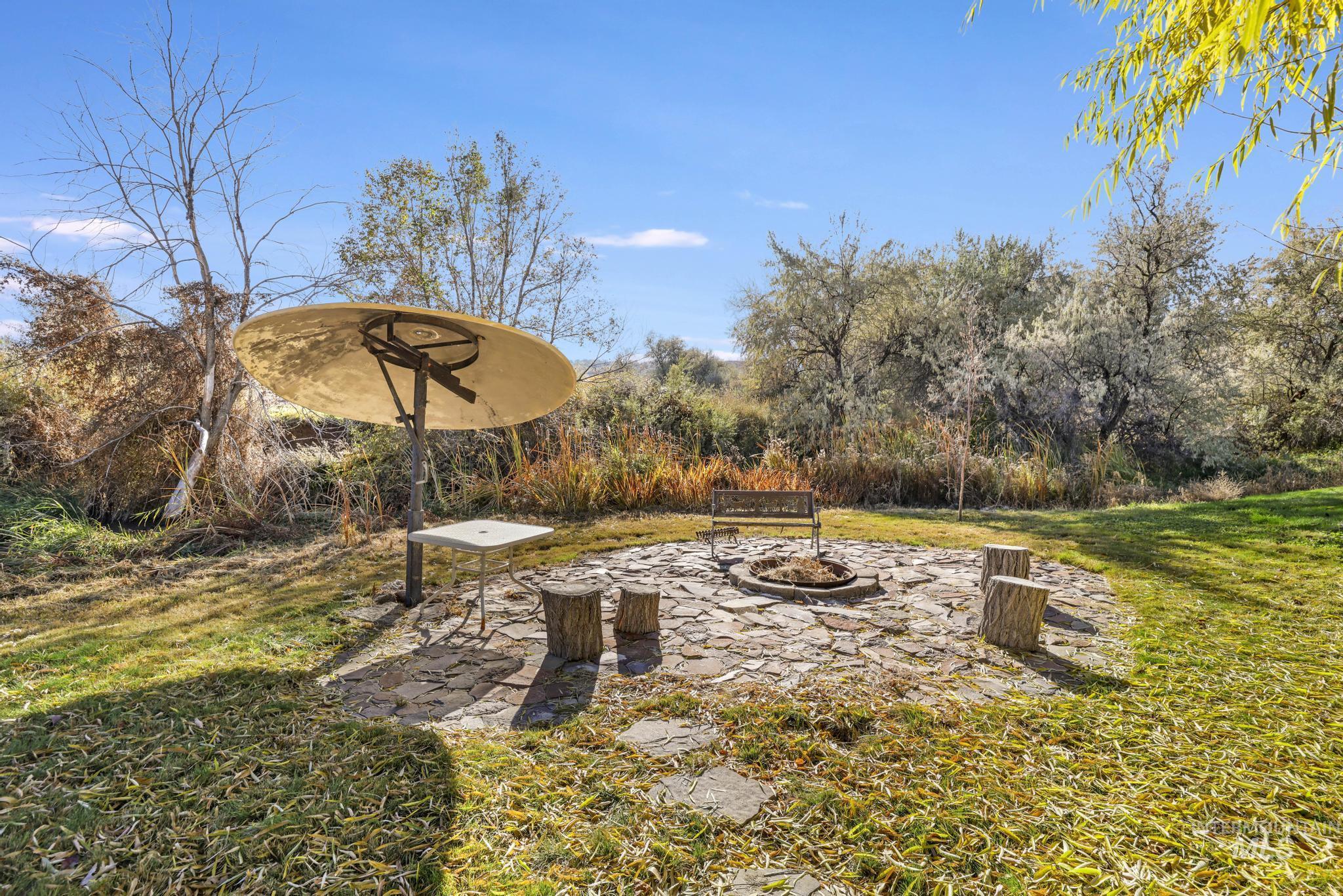 View of green lawn featuring a patio area and an outdoor fire pit