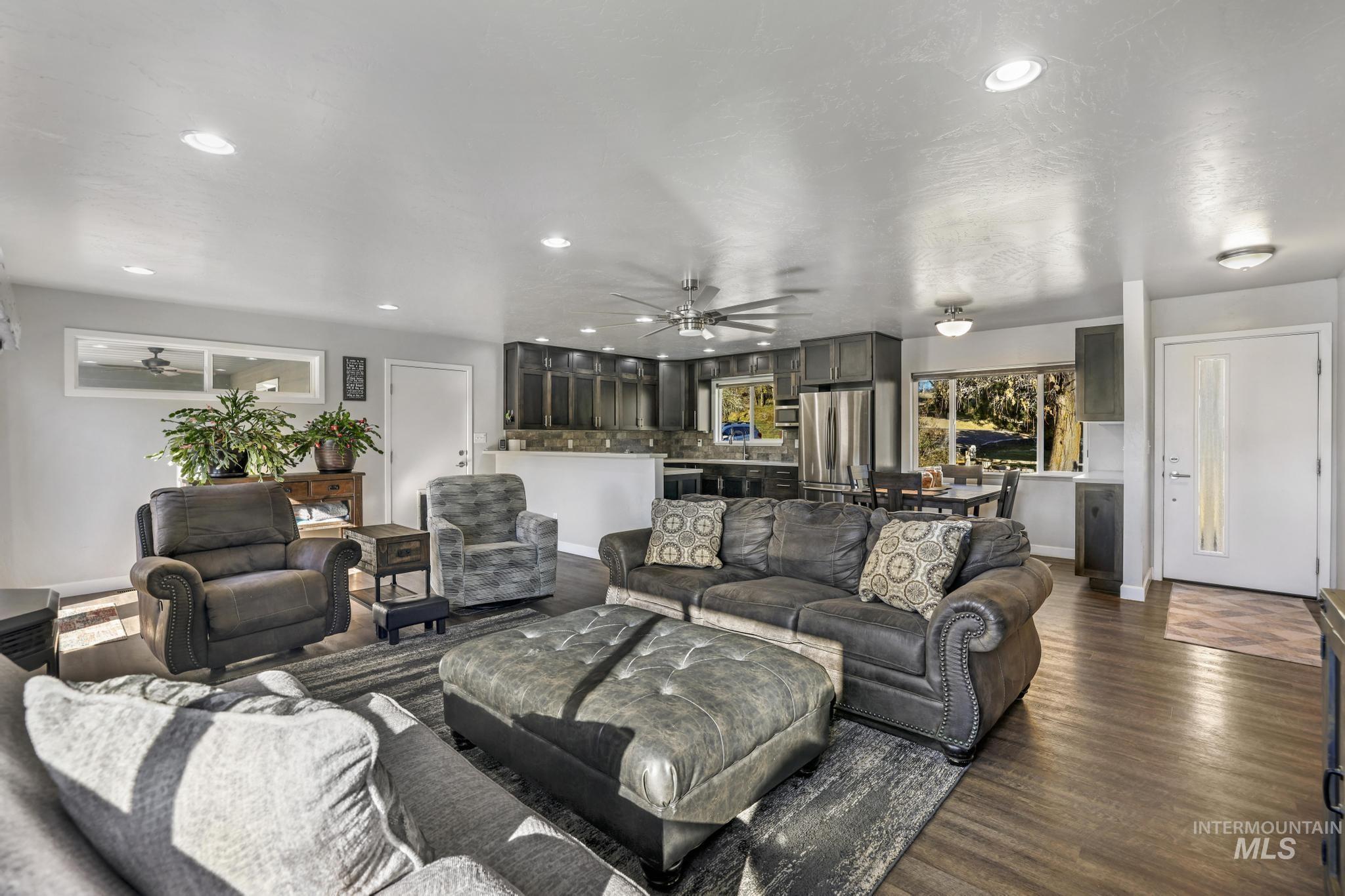 Living room with a ceiling fan, dark wood-type flooring, and recessed lighting