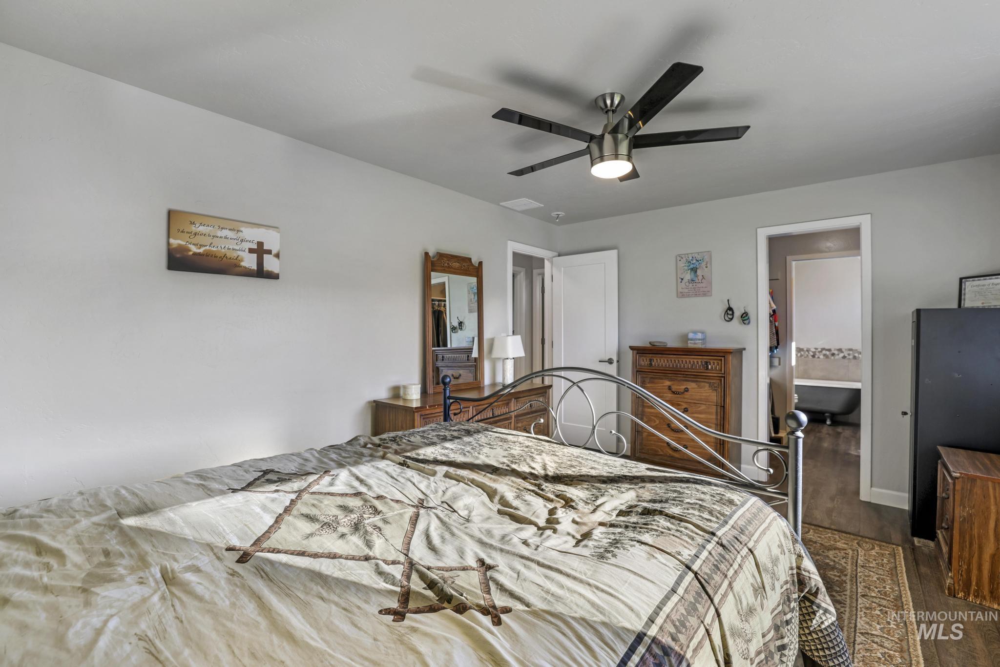 Bedroom with wood finished floors, ceiling fan, and ensuite bath
