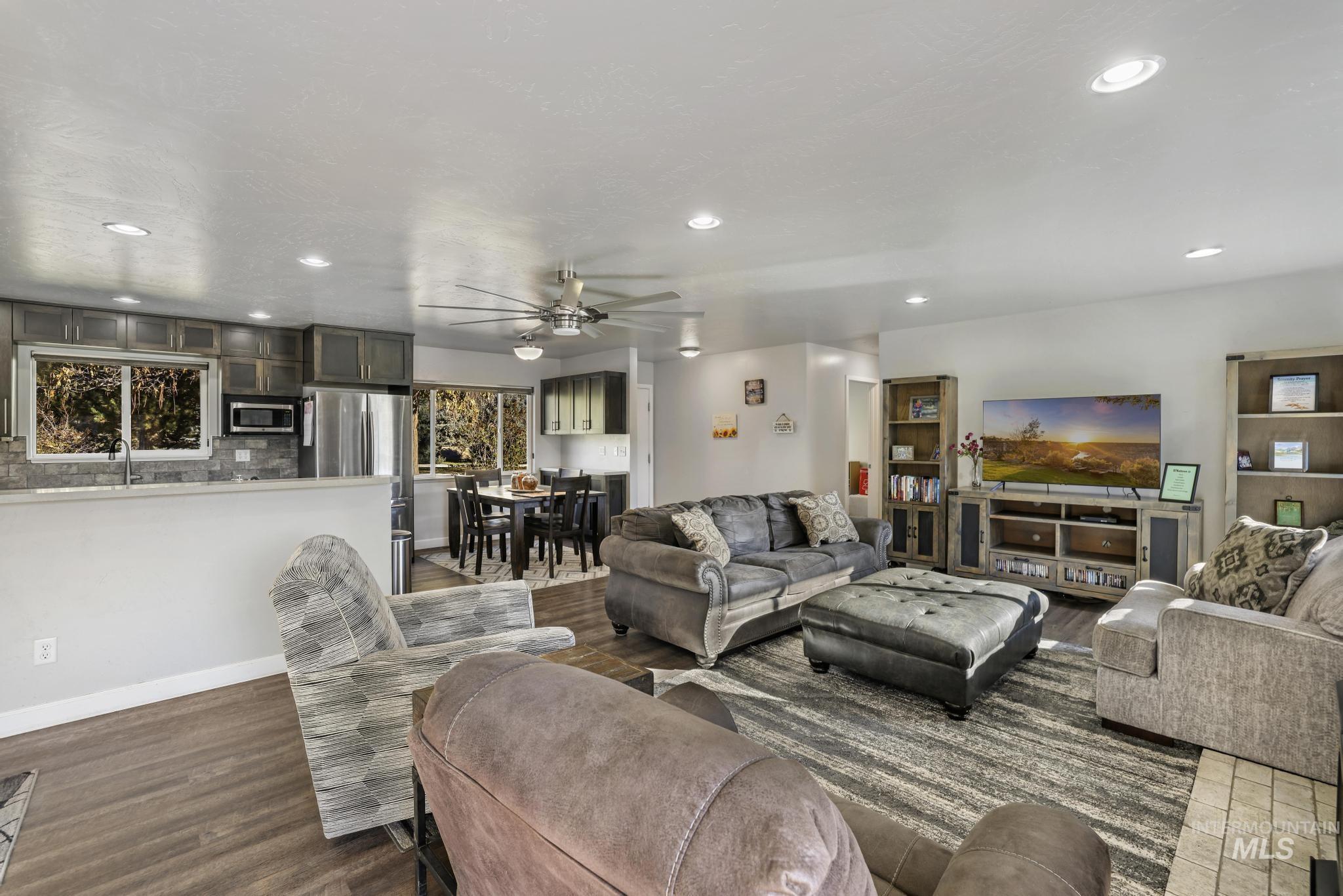 Living room with recessed lighting, ceiling fan, plenty of natural light, and dark wood finished floors