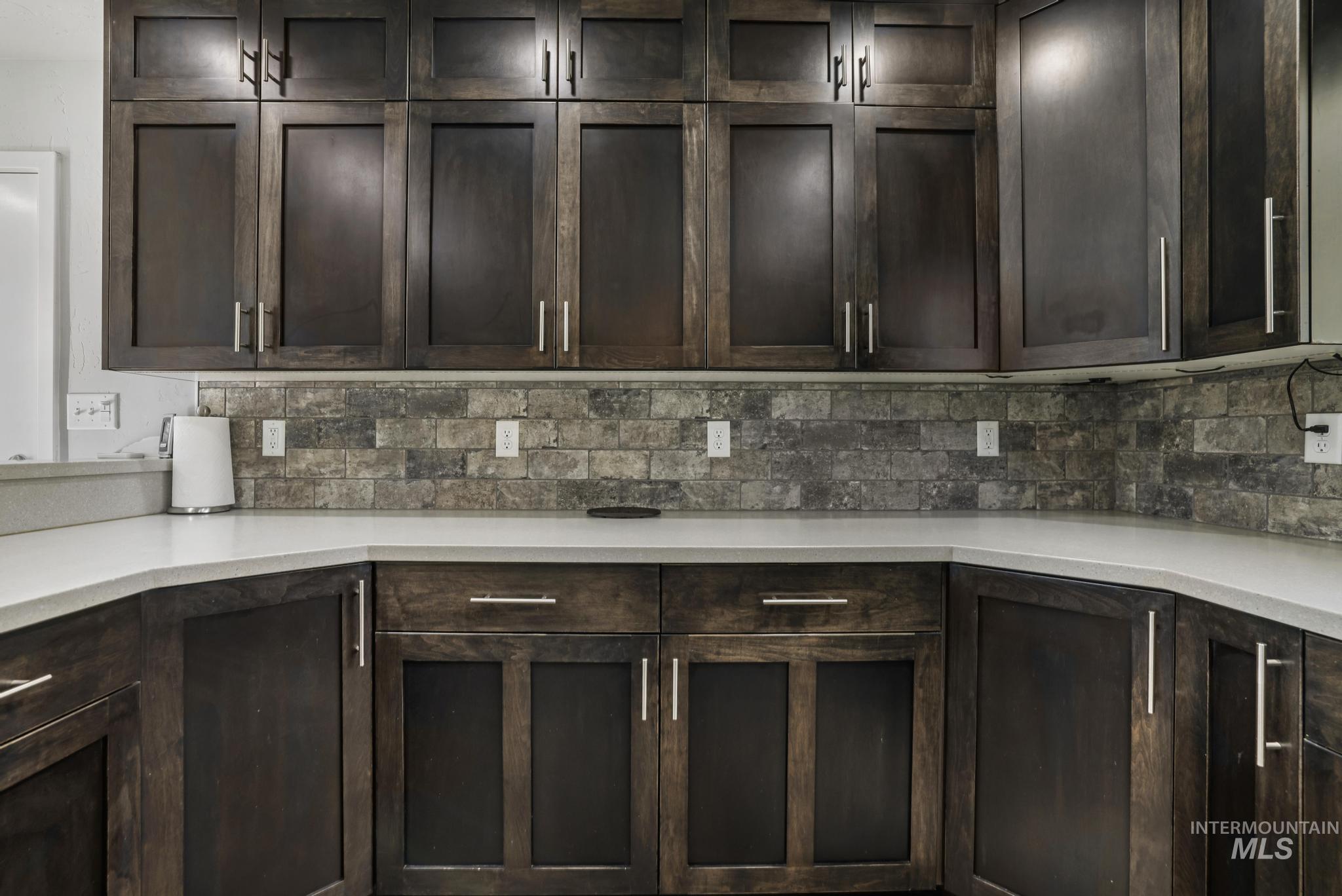 Kitchen with dark brown cabinetry and backsplash