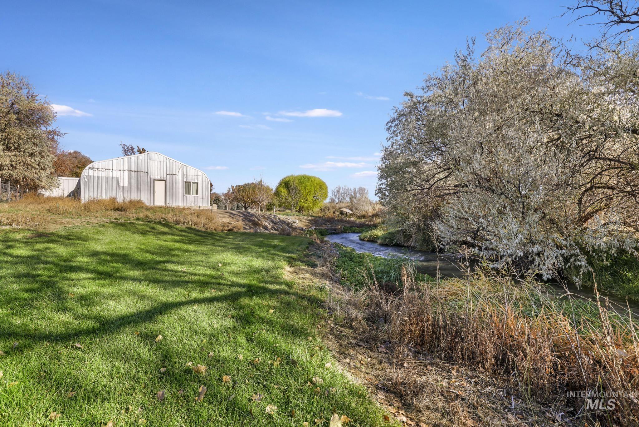 View of green lawn featuring an outbuilding and a water view