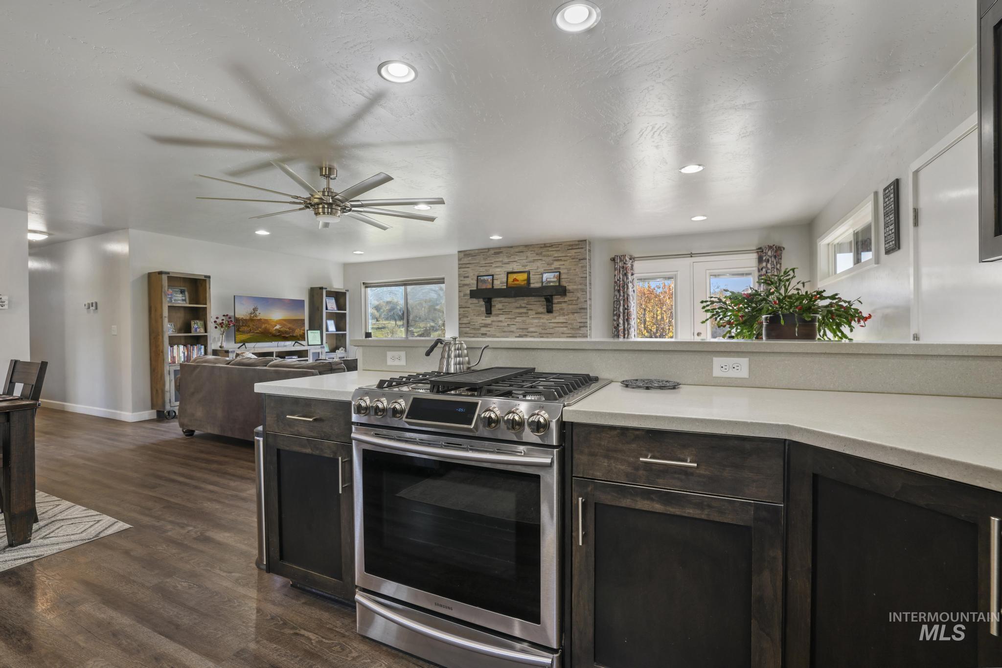 Kitchen featuring stainless steel range with gas stovetop, dark brown cabinetry, dark wood-type flooring, recessed lighting, and open floor plan