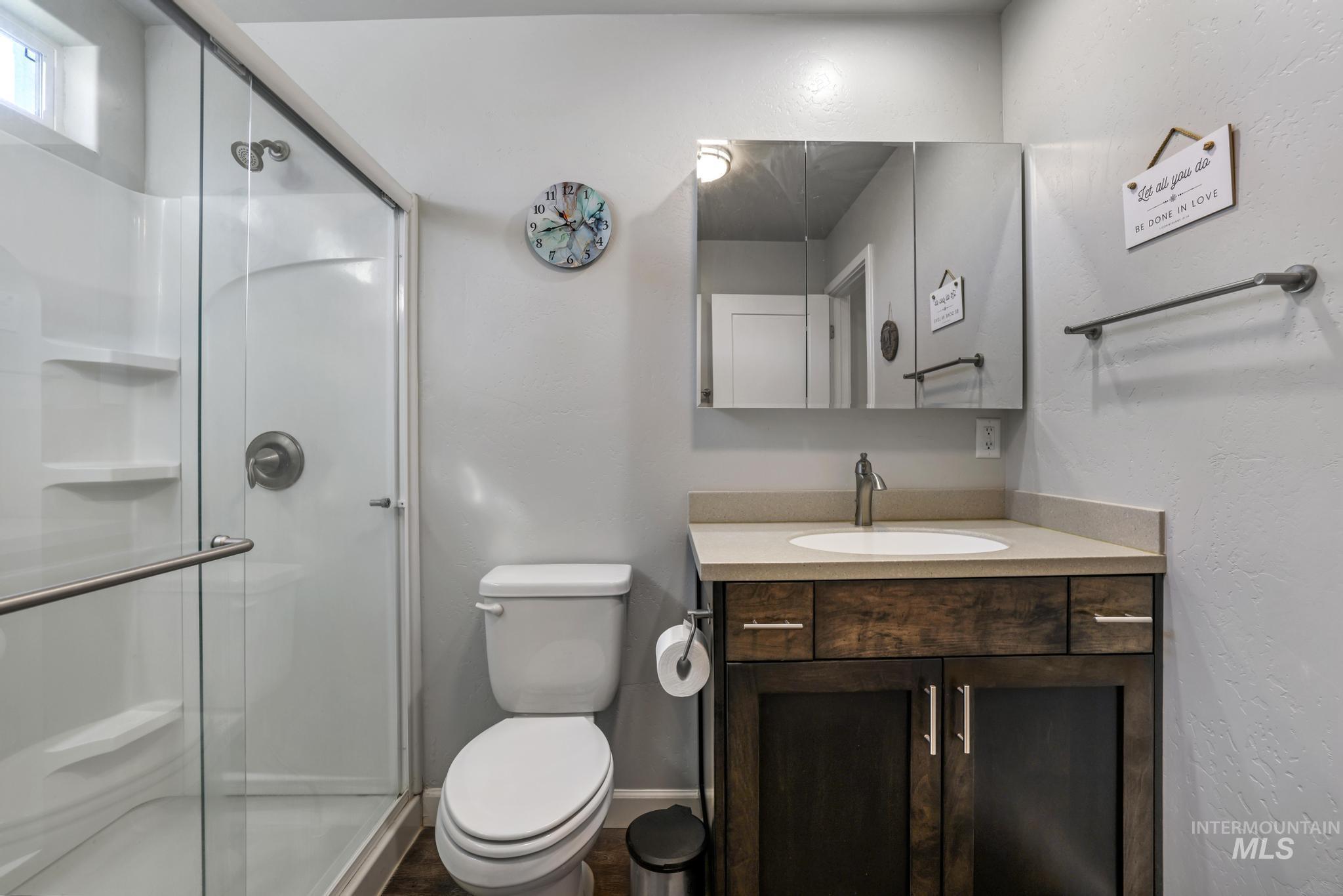 Full bathroom featuring vanity, a shower stall, and a textured wall