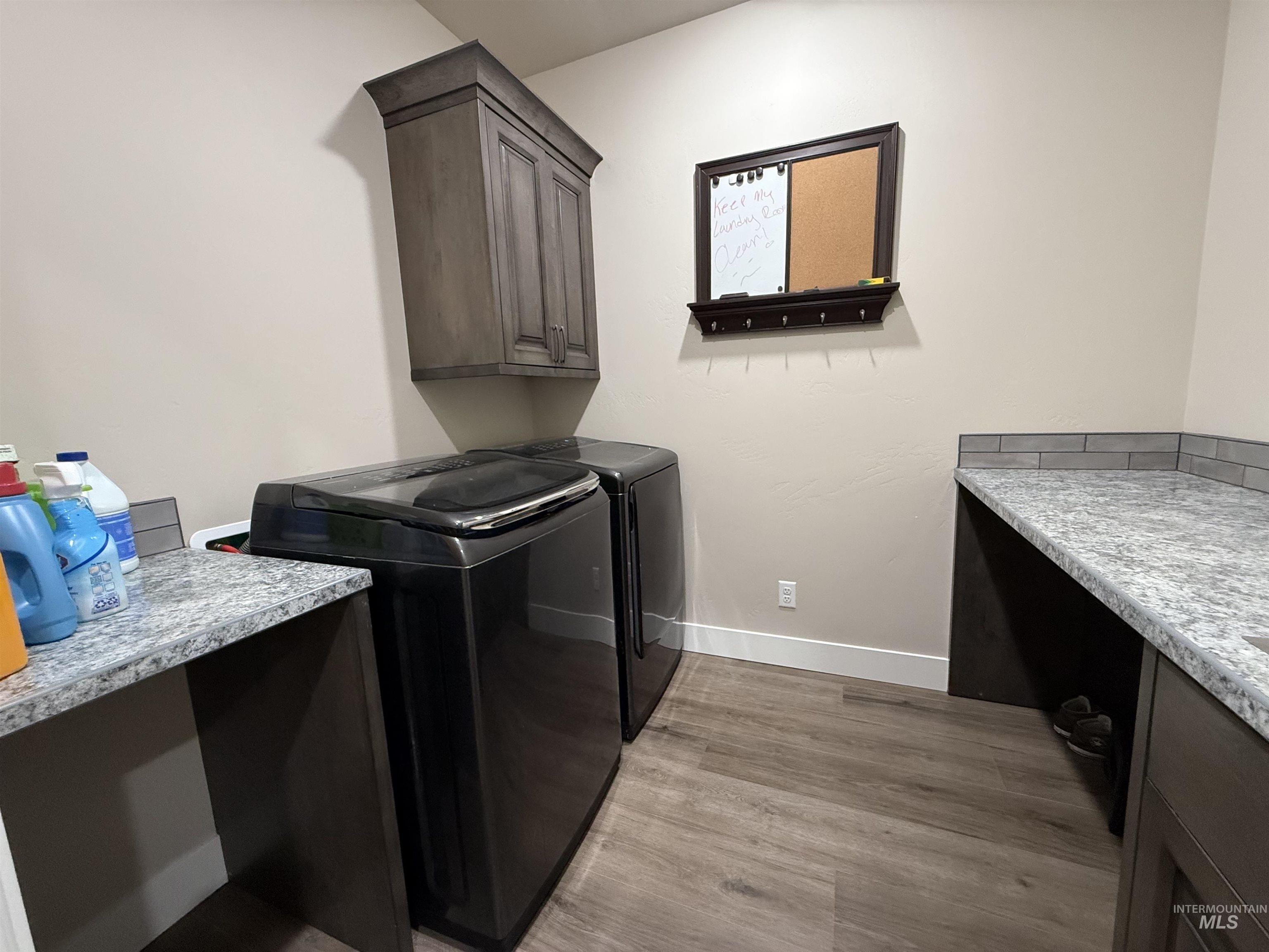 Washroom with washing machine and clothes dryer, light wood-style floors, and cabinet space