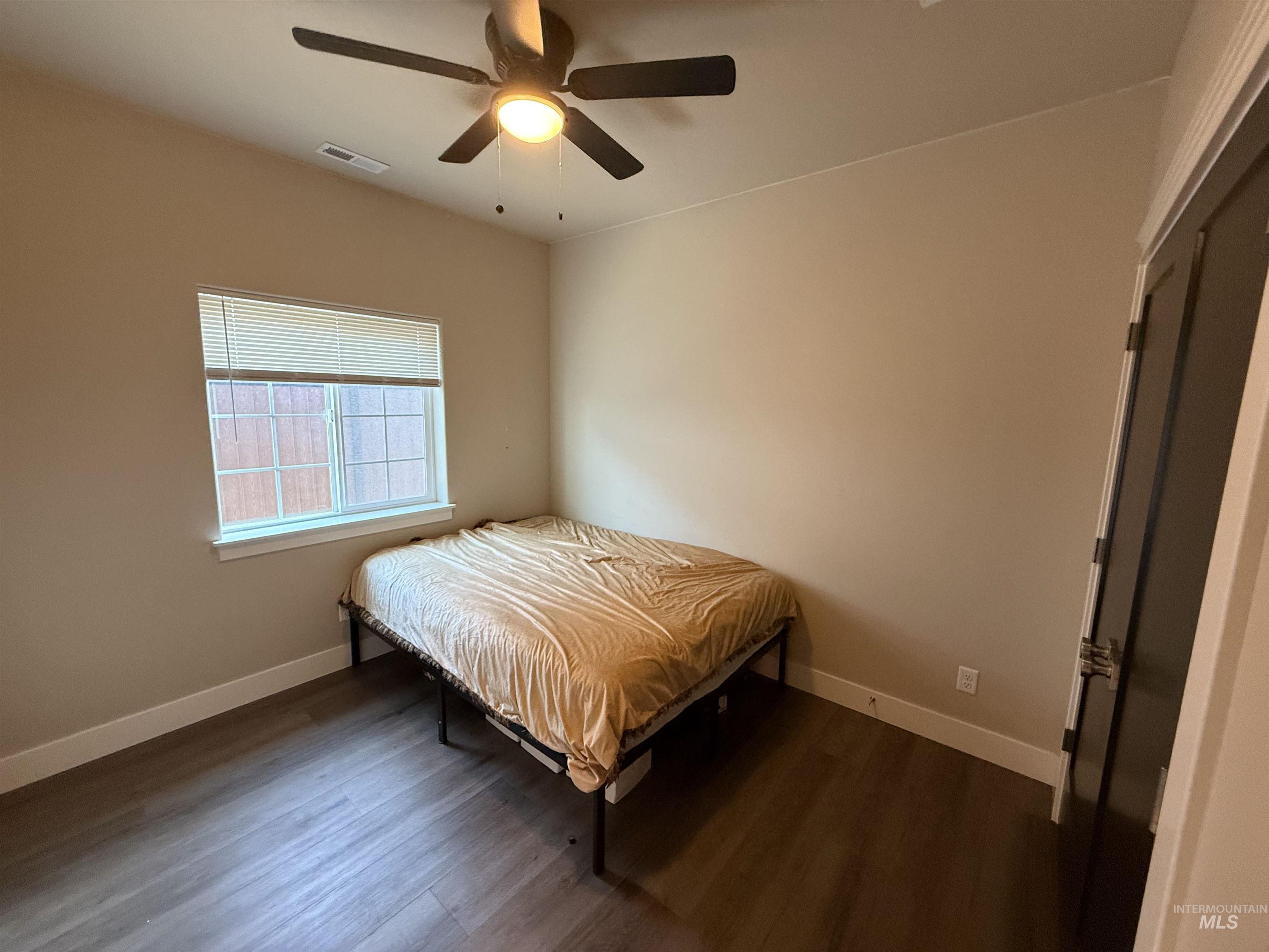 Bedroom with dark wood-style floors and ceiling fan