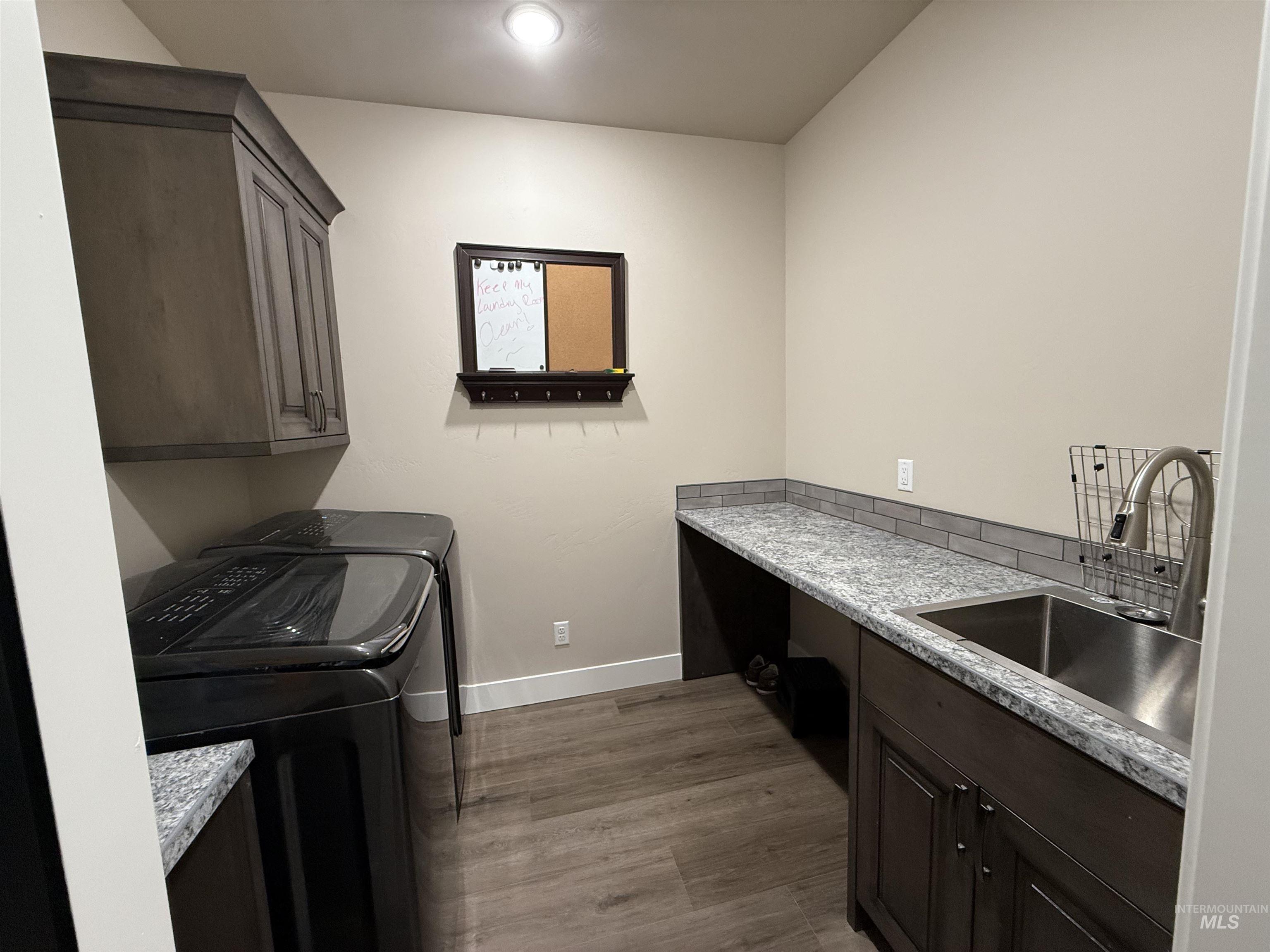 Laundry room with cabinet space, washer and dryer, and dark wood finished floors