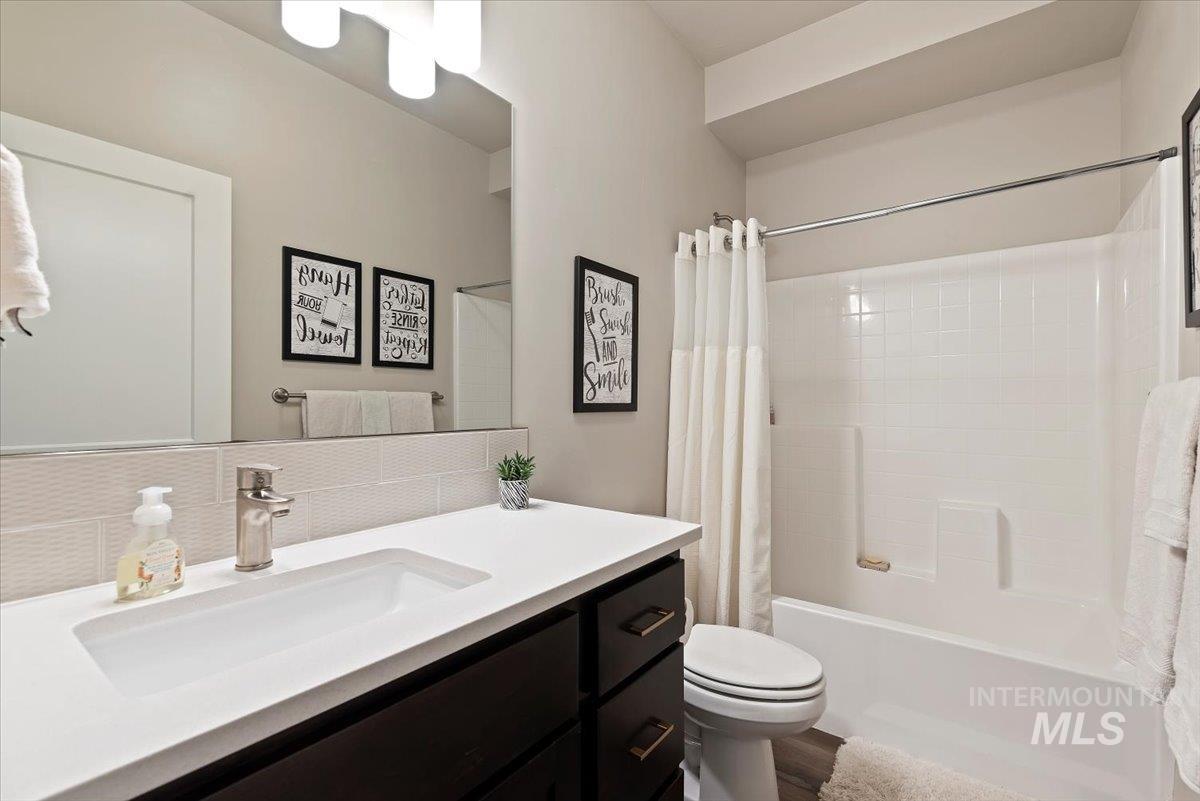 Bathroom featuring vanity, shower / bath combination with curtain, and backsplash