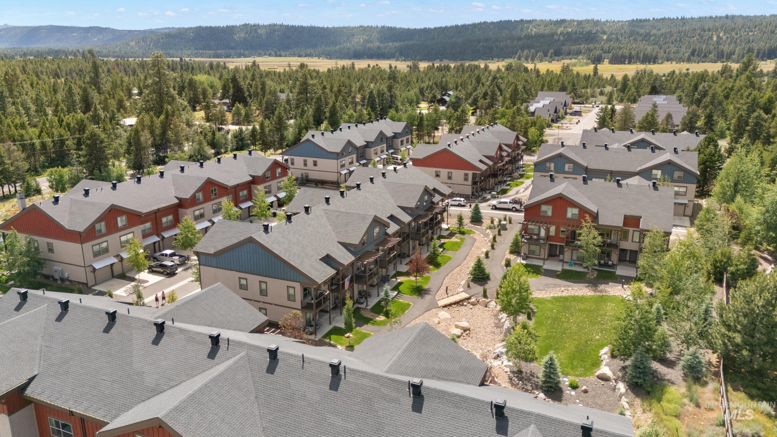 Community of multi-story residences featuring pitched roofs, individual balconies, and surrounding mature trees
