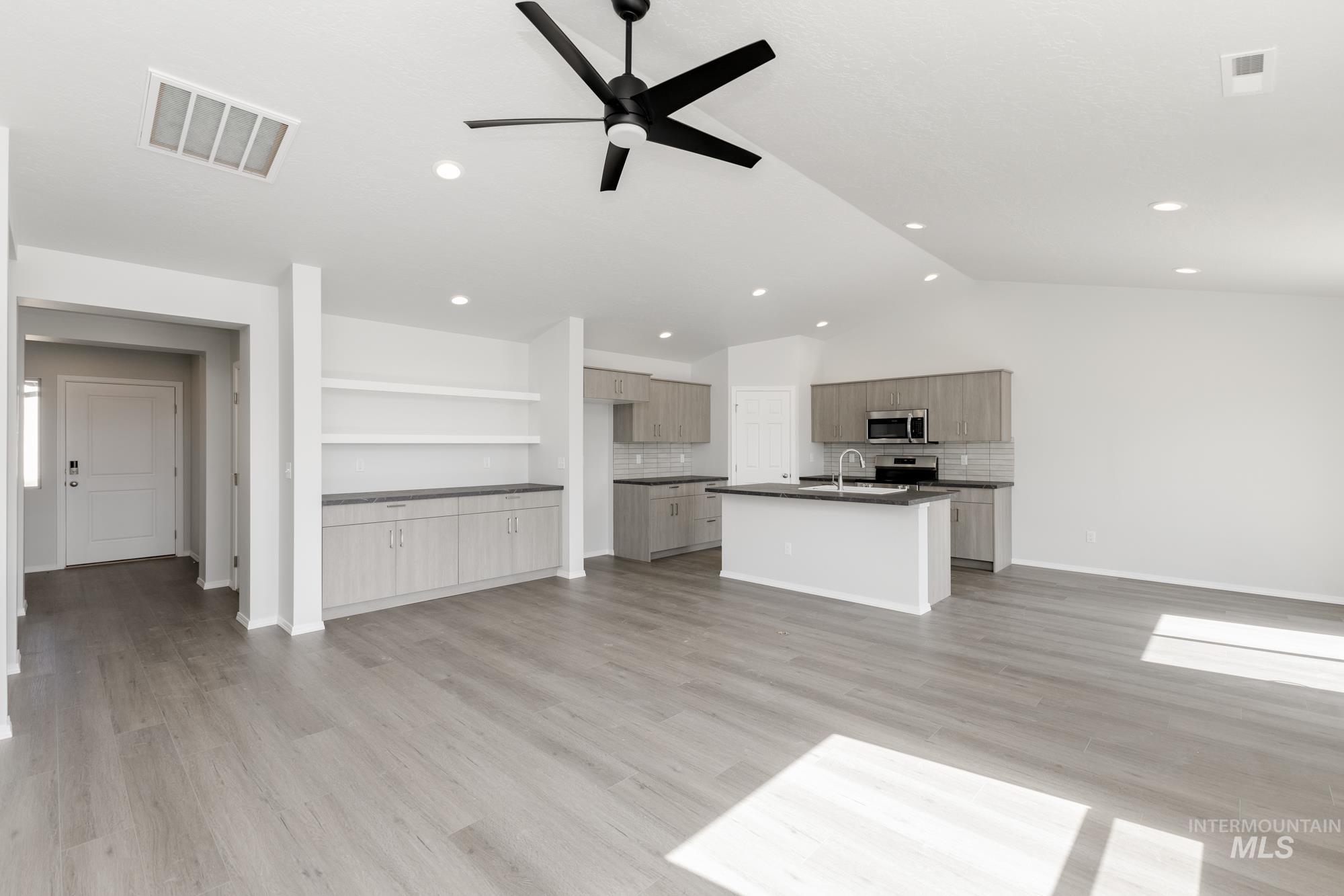 Unfurnished living room featuring light wood-style floors, ceiling fan, lofted ceiling, and recessed lighting