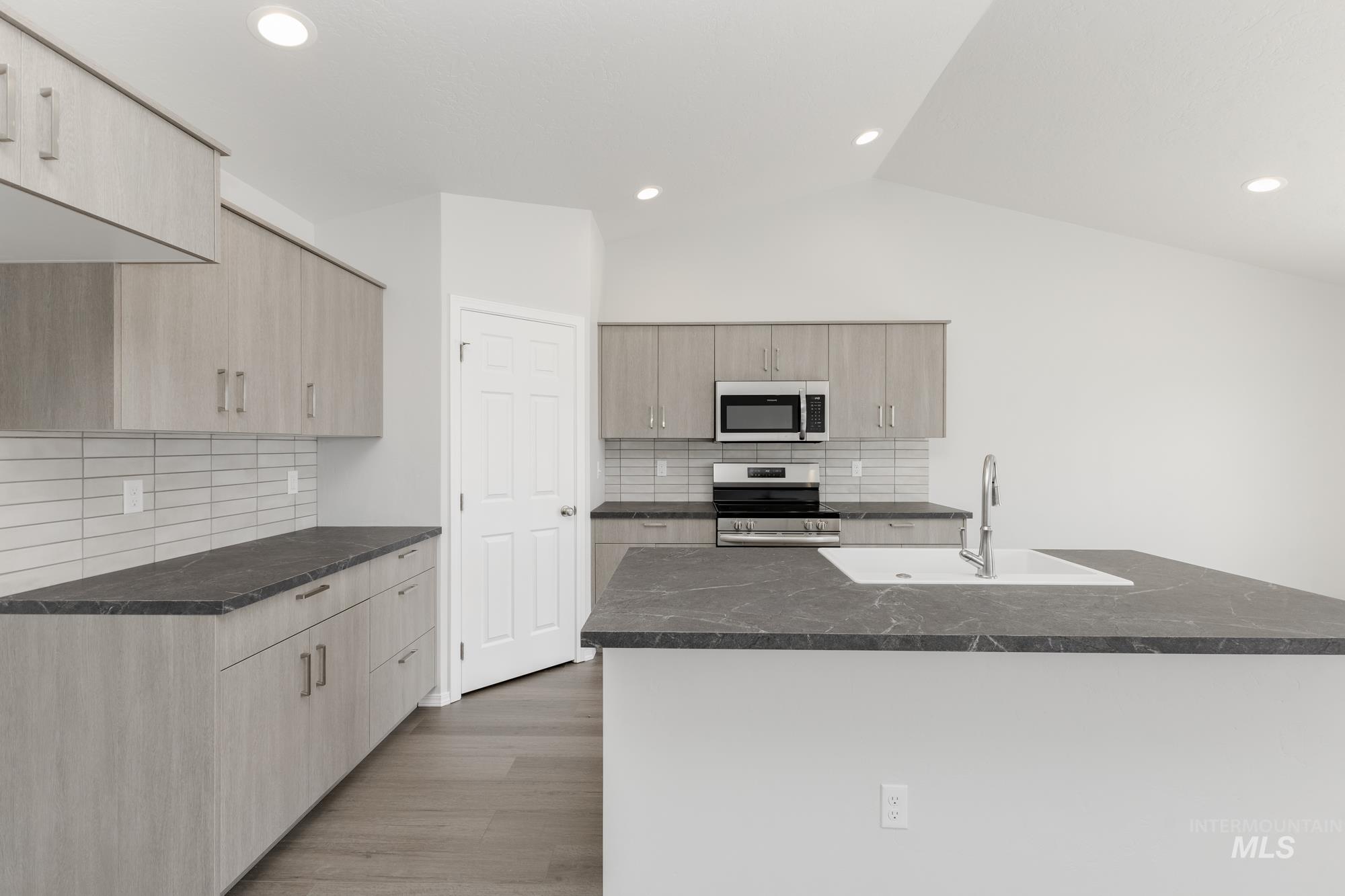 Kitchen featuring appliances with stainless steel finishes, light wood-type flooring, backsplash, light brown cabinets, and recessed lighting
