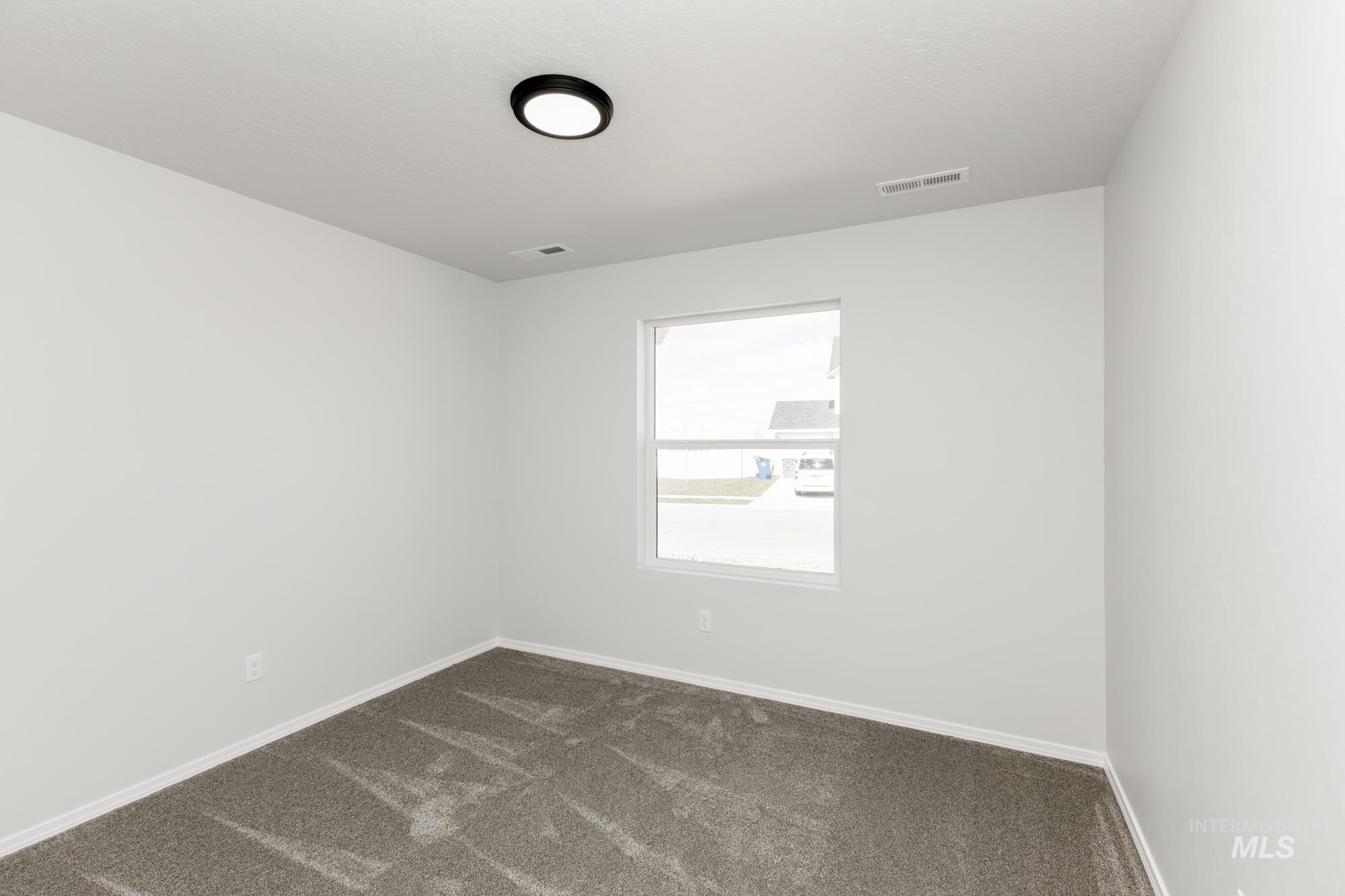 Empty room featuring dark carpet and baseboards
