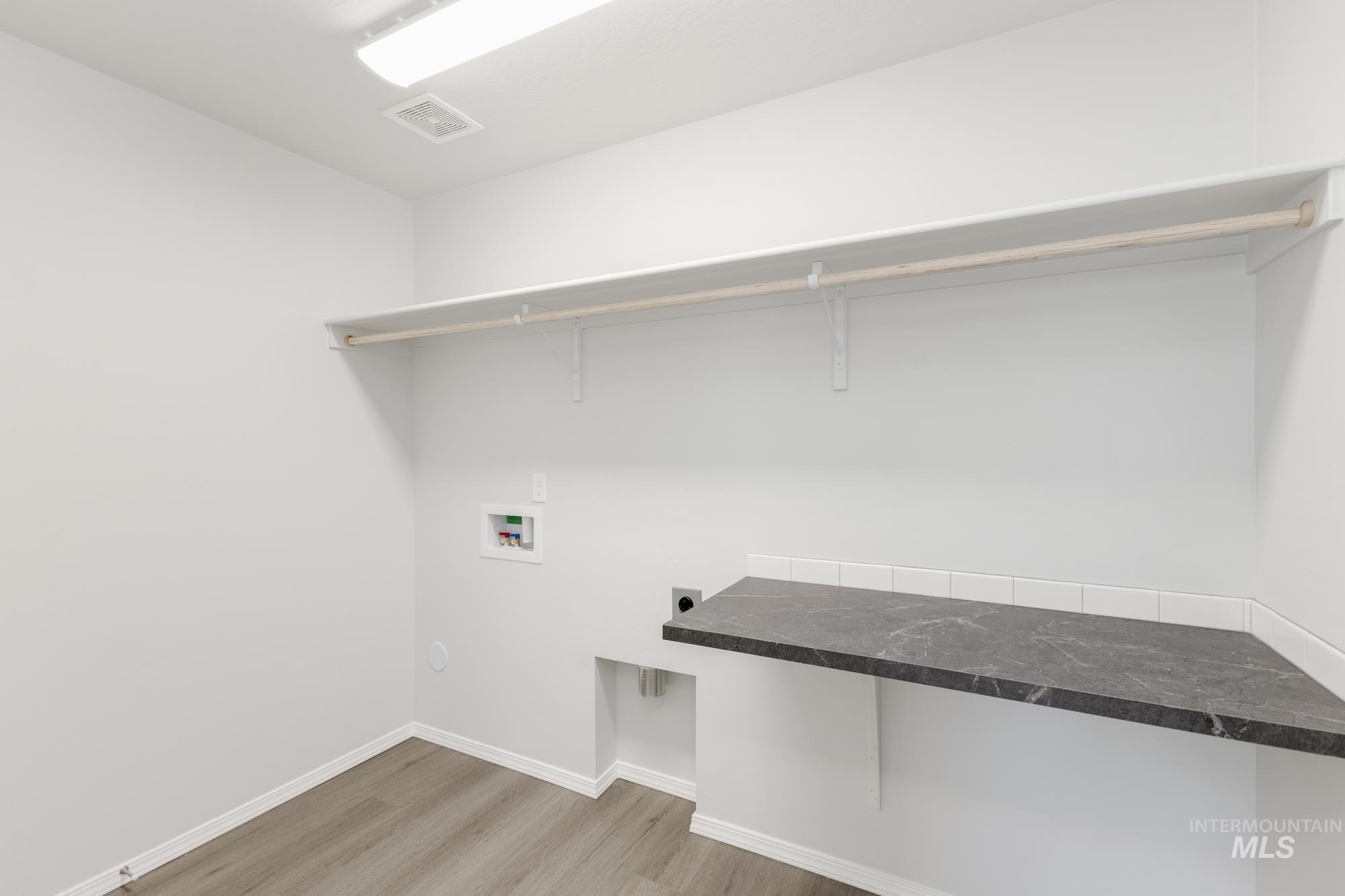 Washroom with light wood finished floors, hookup for an electric dryer, and washer hookup