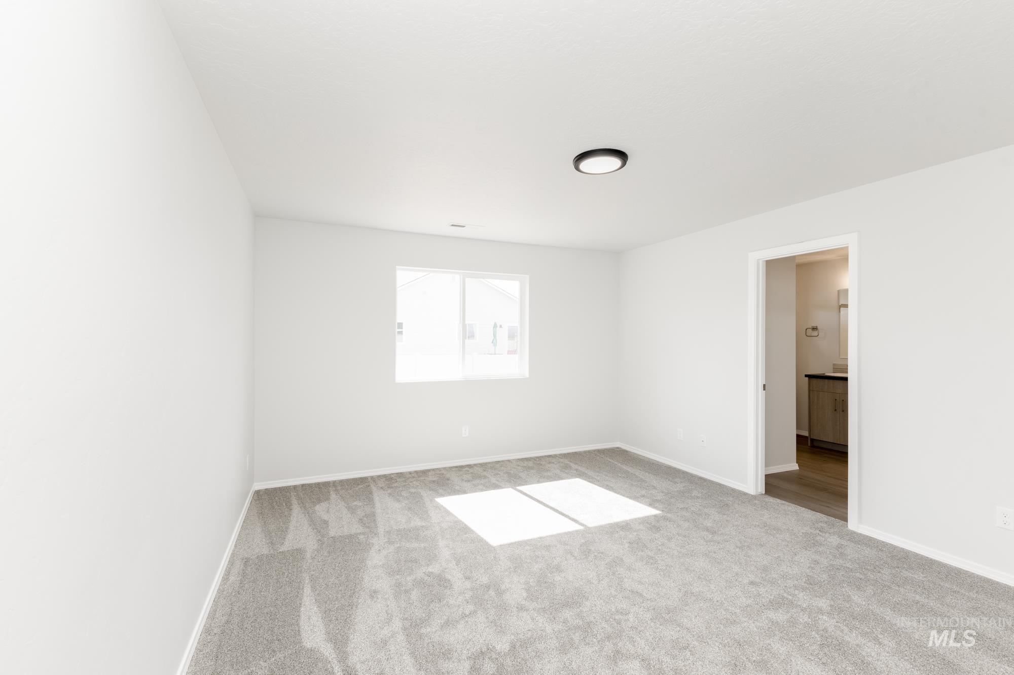 Spare room featuring light carpet and baseboards