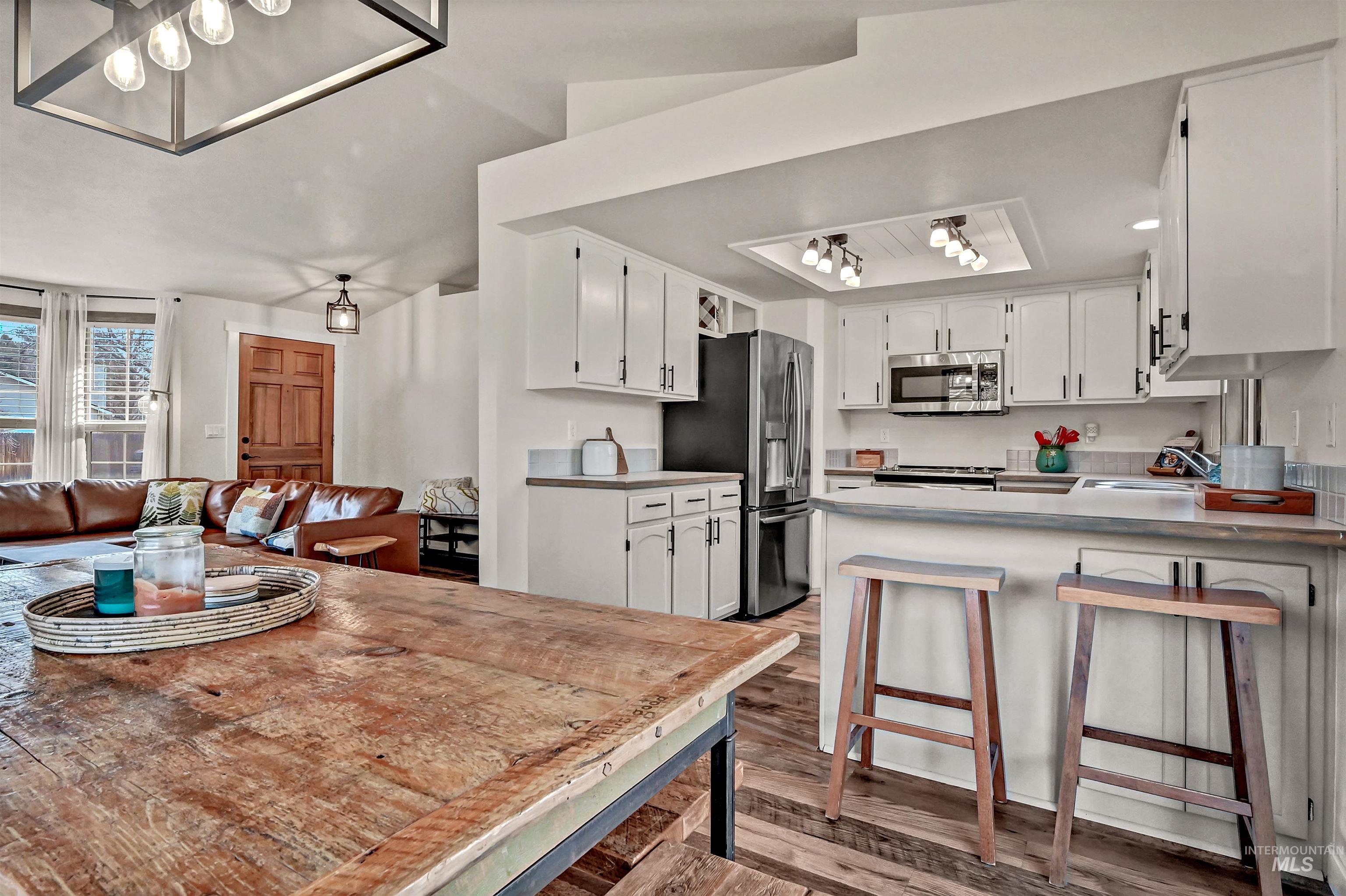 Kitchen featuring white cabinetry, a peninsula, open floor plan, and dark wood finished floors