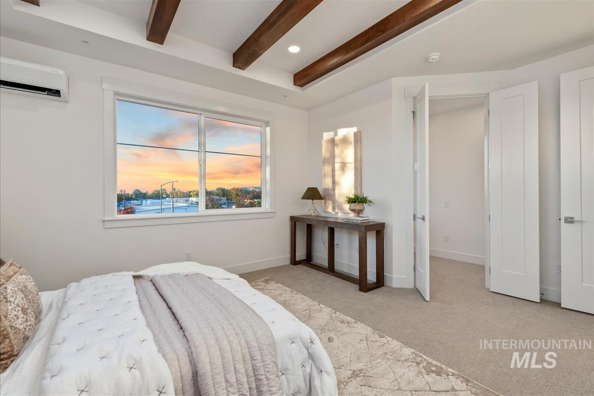 Open-concept room featuring exposed wood ceiling beams and a large window