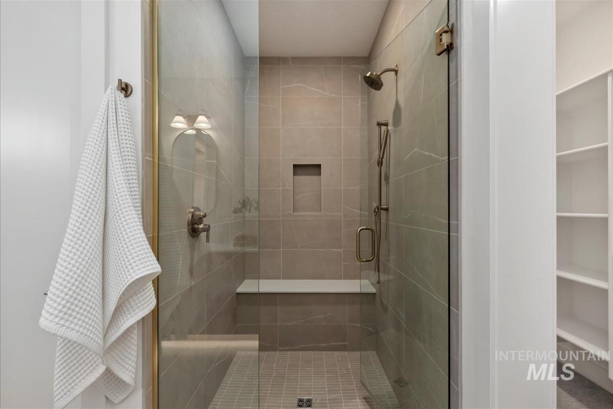 Walk-in shower with clear glass enclosure and brass-finish fixtures