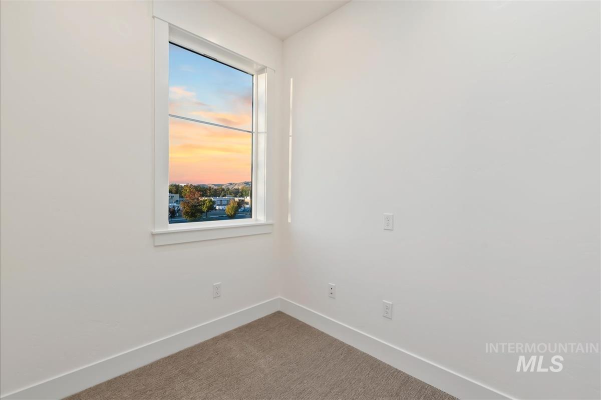 Bright room featuring a large window, neutral carpeting, white baseboards, and clean white walls