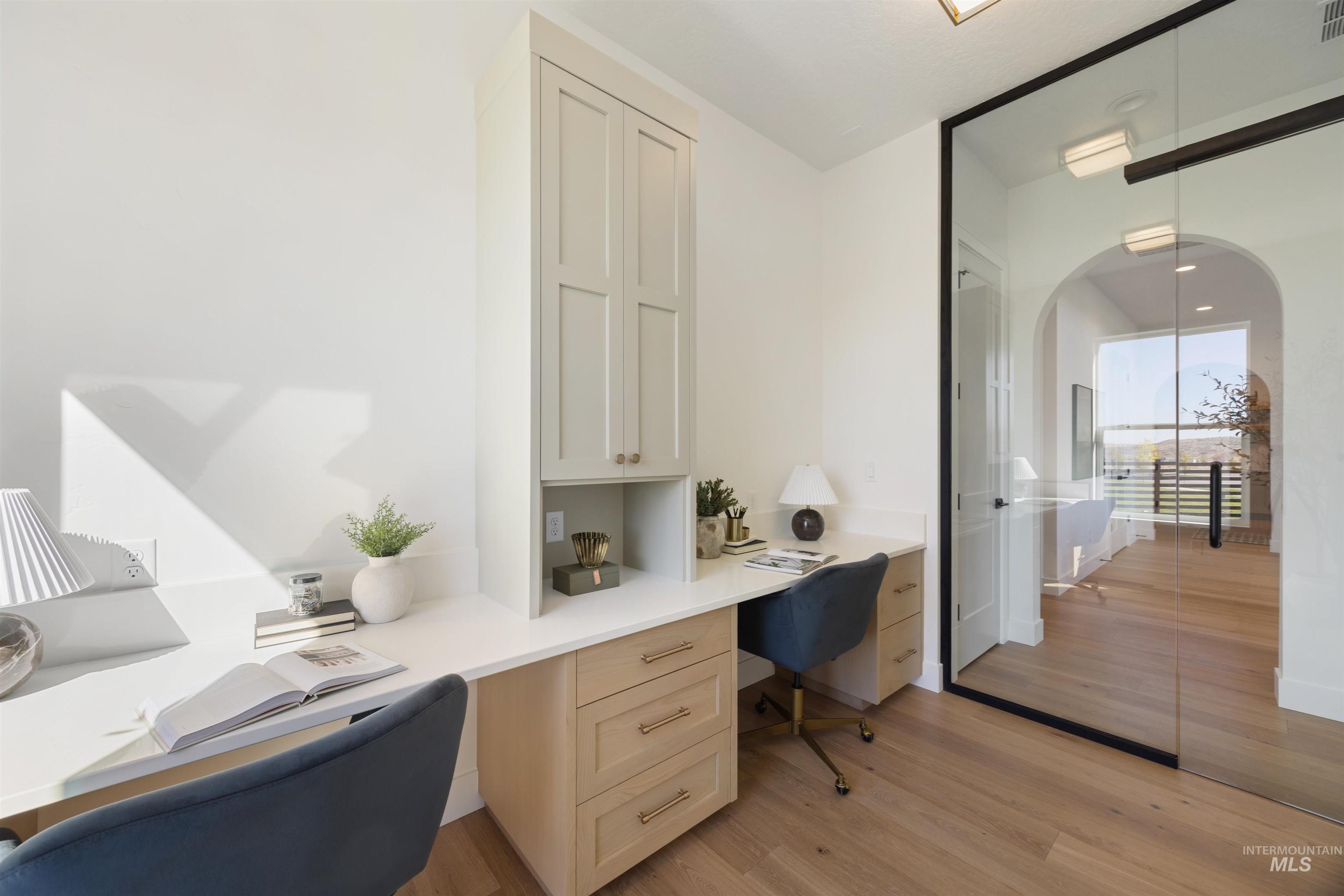 Home office with built in desk and light wood-style flooring