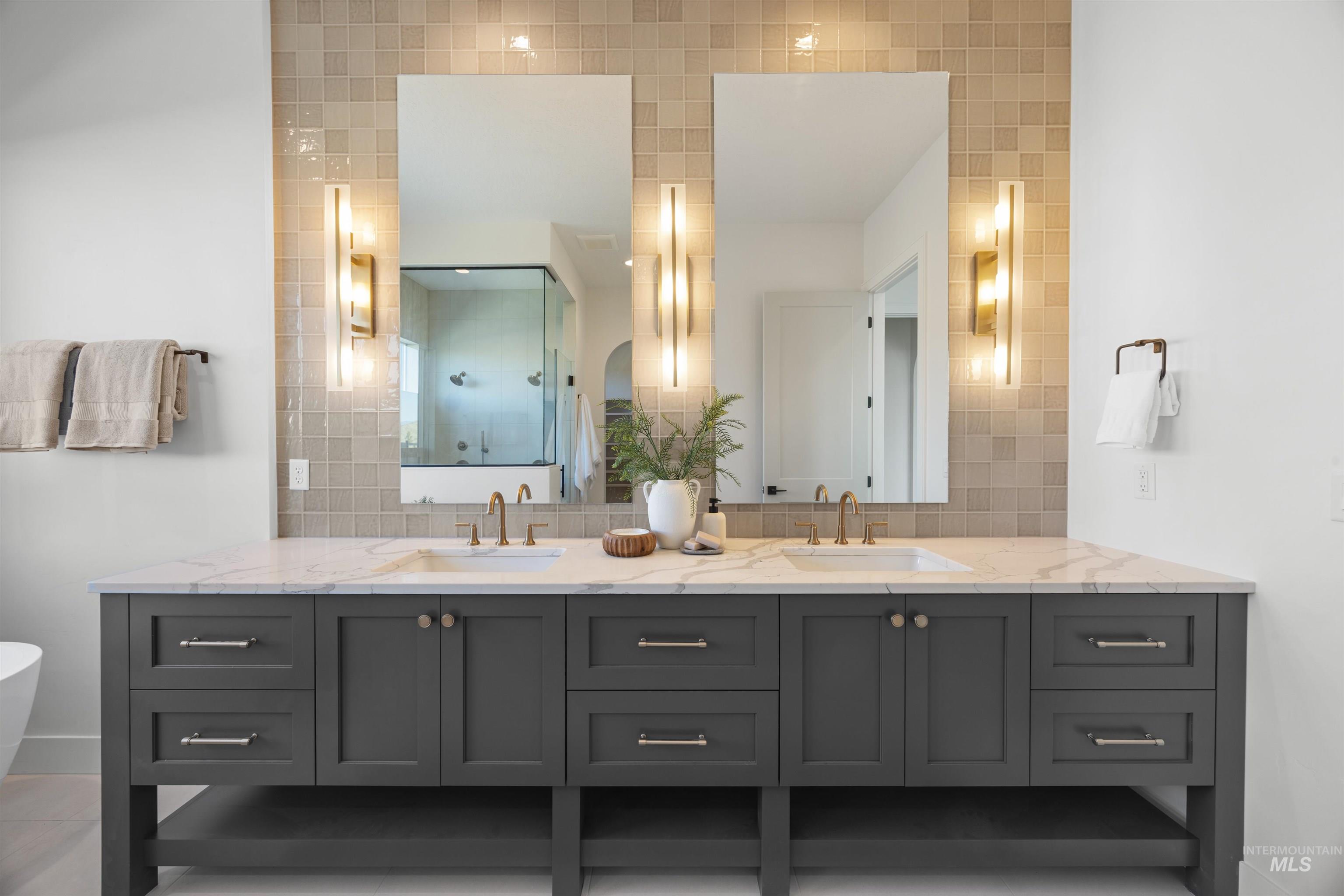 Bathroom featuring double vanity, tasteful backsplash, walk in shower, and tile walls