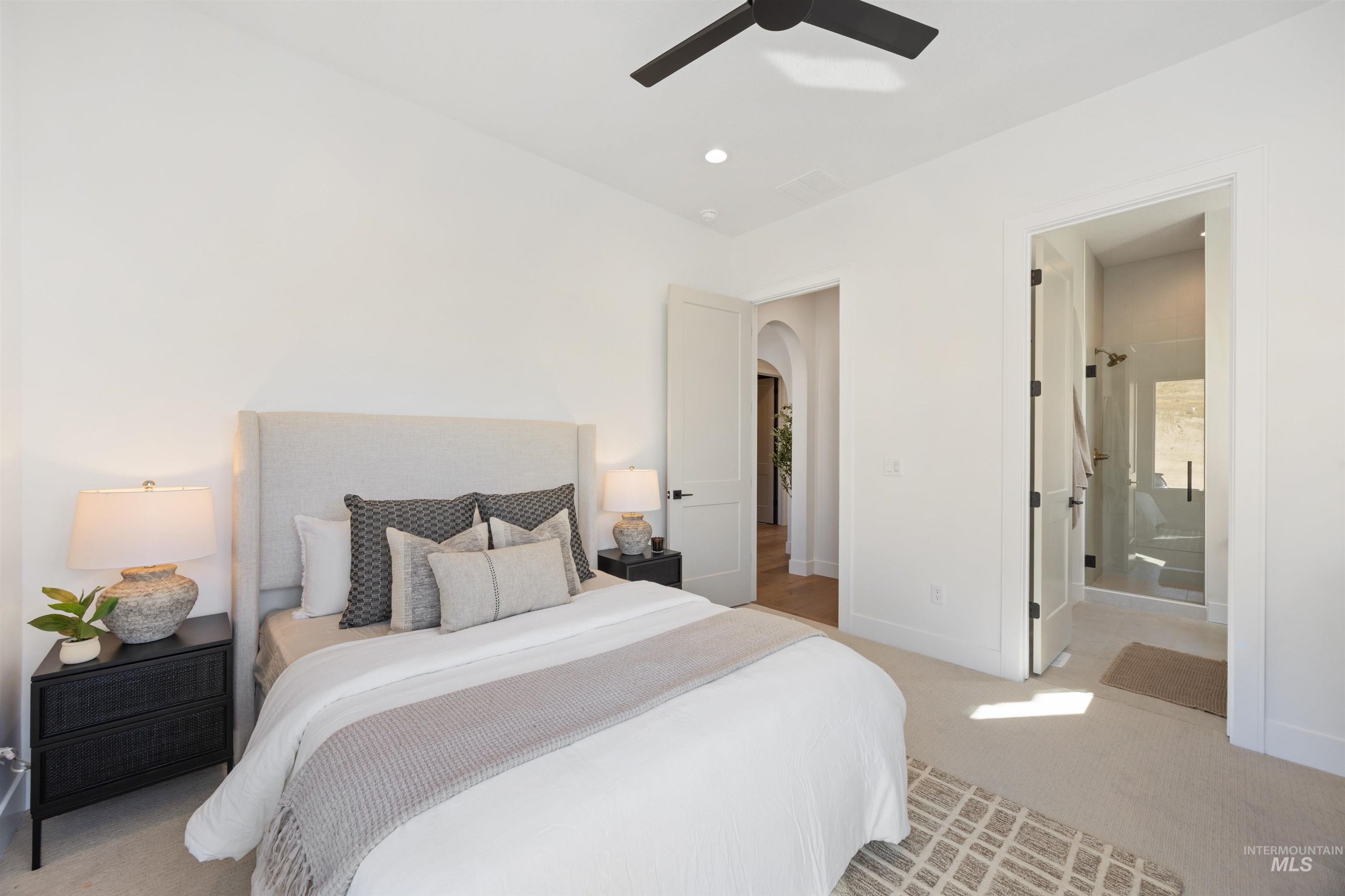Bedroom with light colored carpet, ensuite bath, arched walkways, a ceiling fan, and recessed lighting