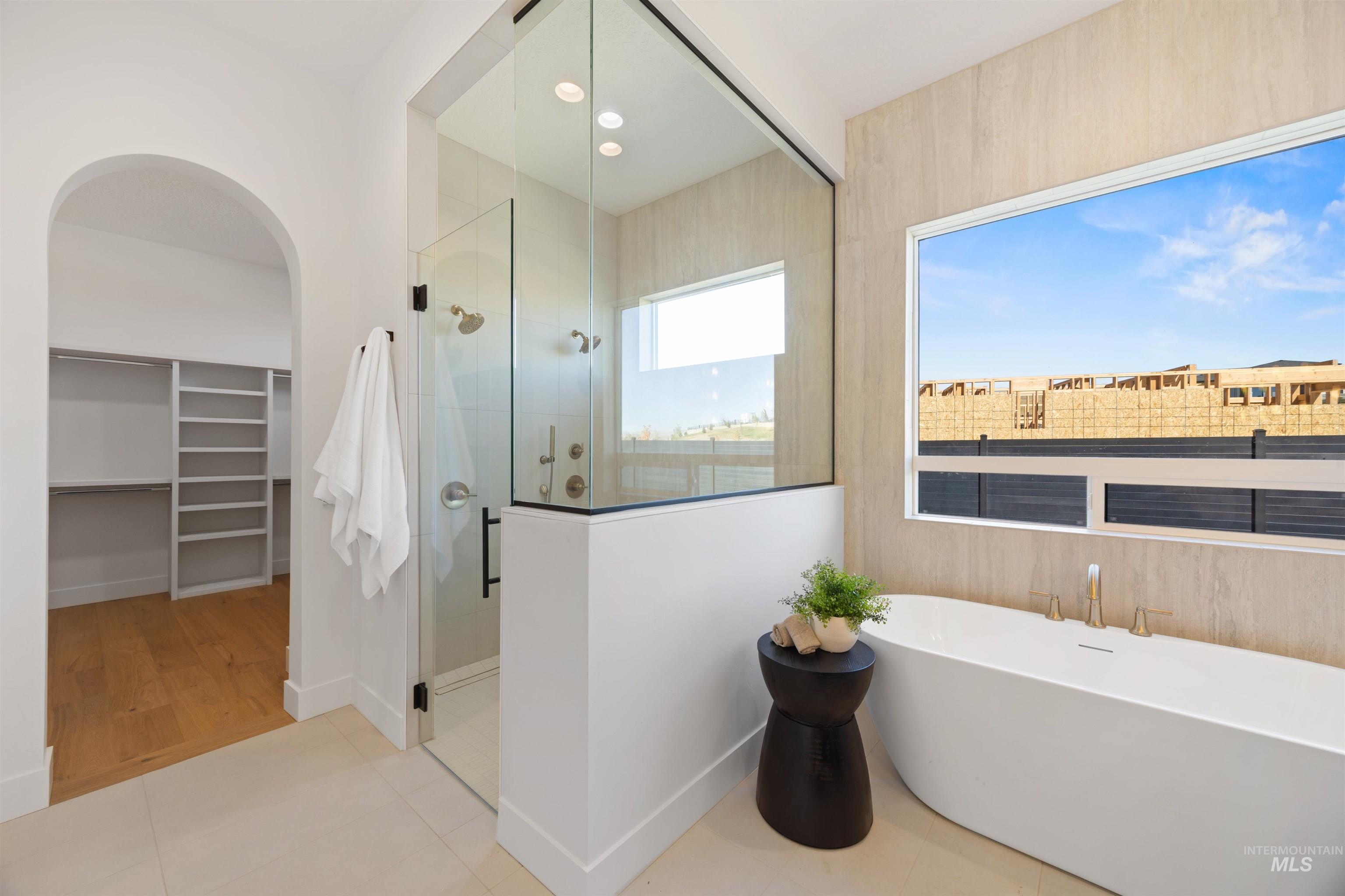 Bathroom featuring a stall shower, a soaking tub, a spacious closet, light tile patterned floors, and recessed lighting