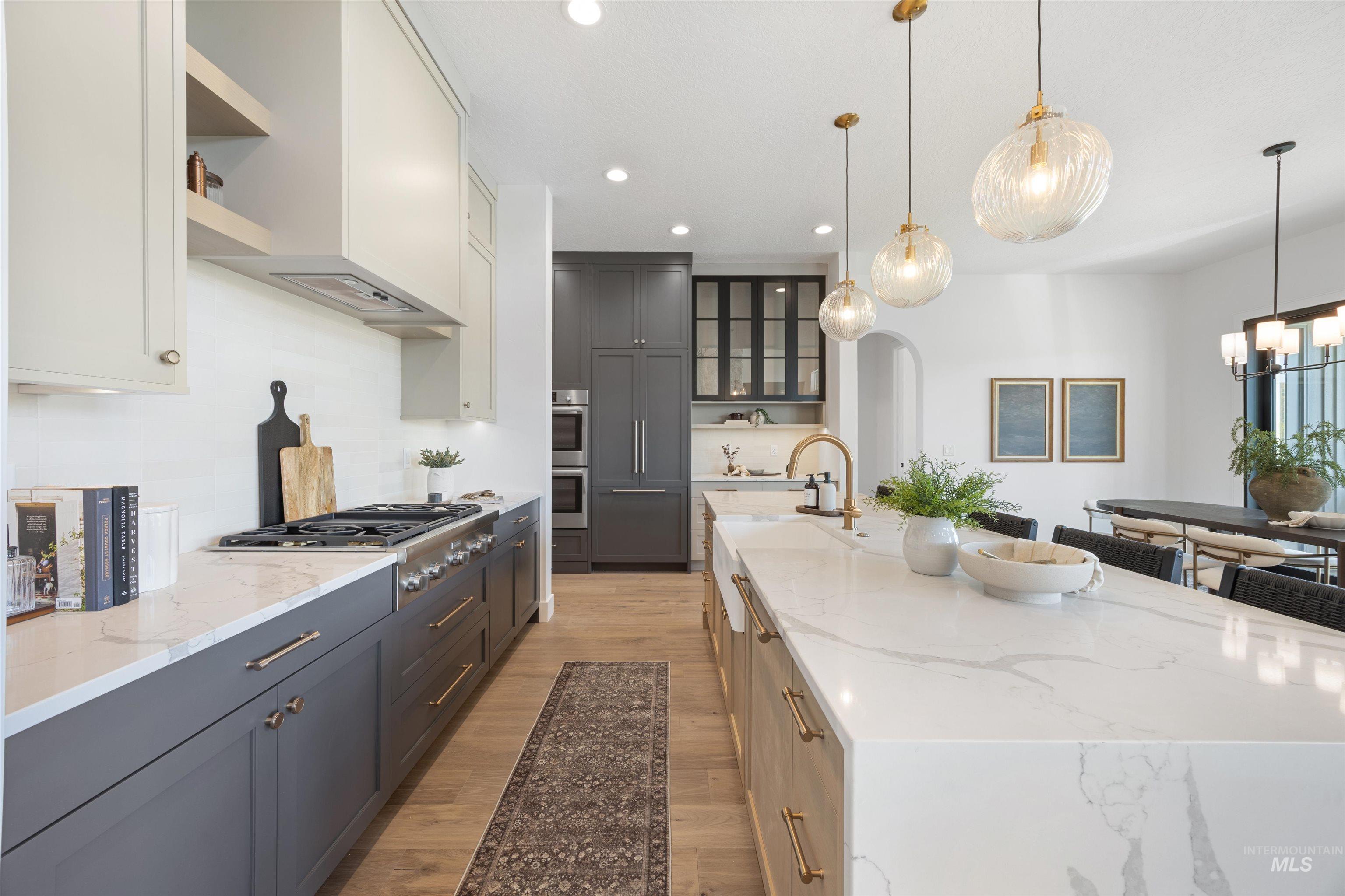 Kitchen with light stone countertops, gray cabinetry, light wood finished floors, glass insert cabinets, and recessed lighting