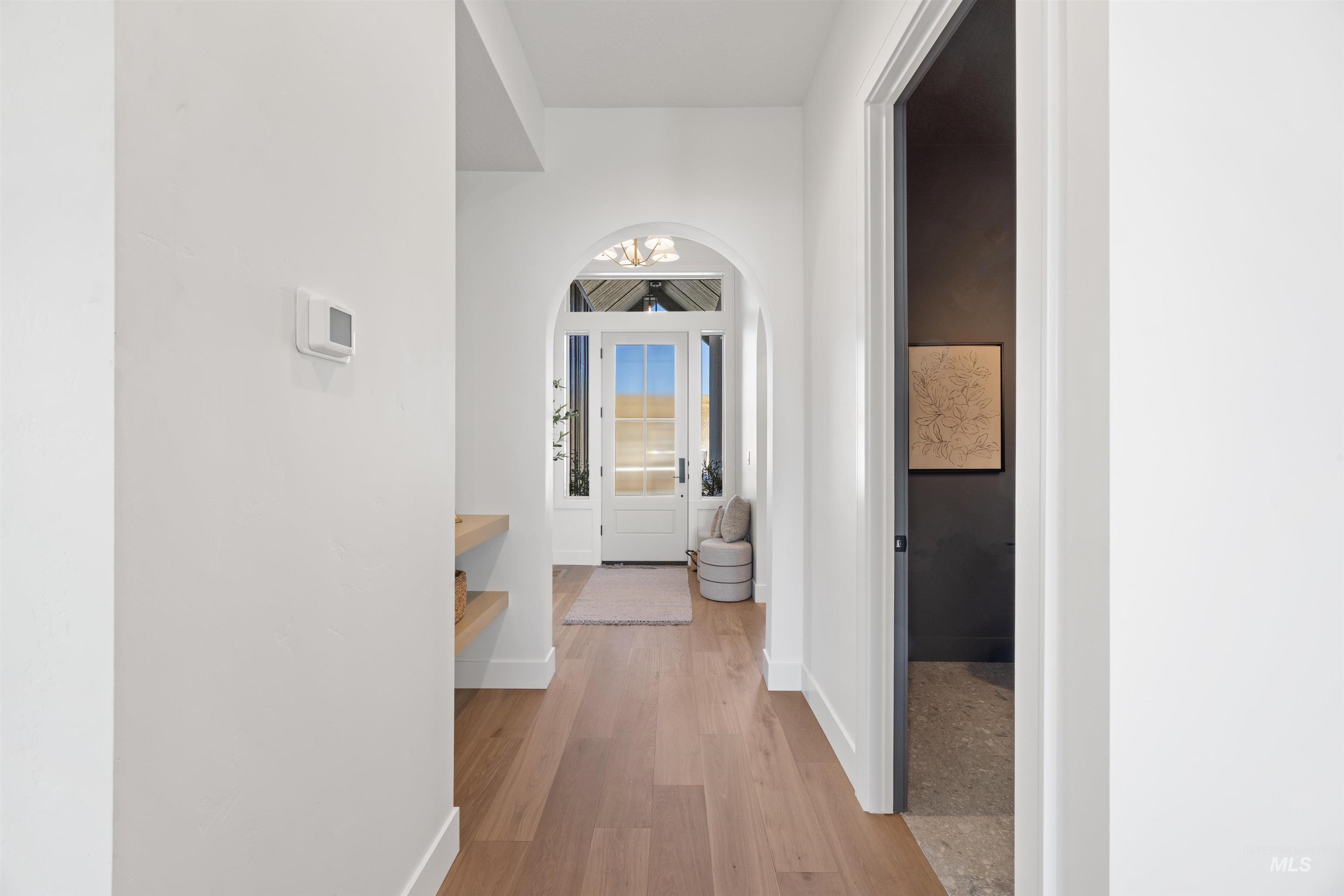 Corridor with light wood-style flooring and arched walkways
