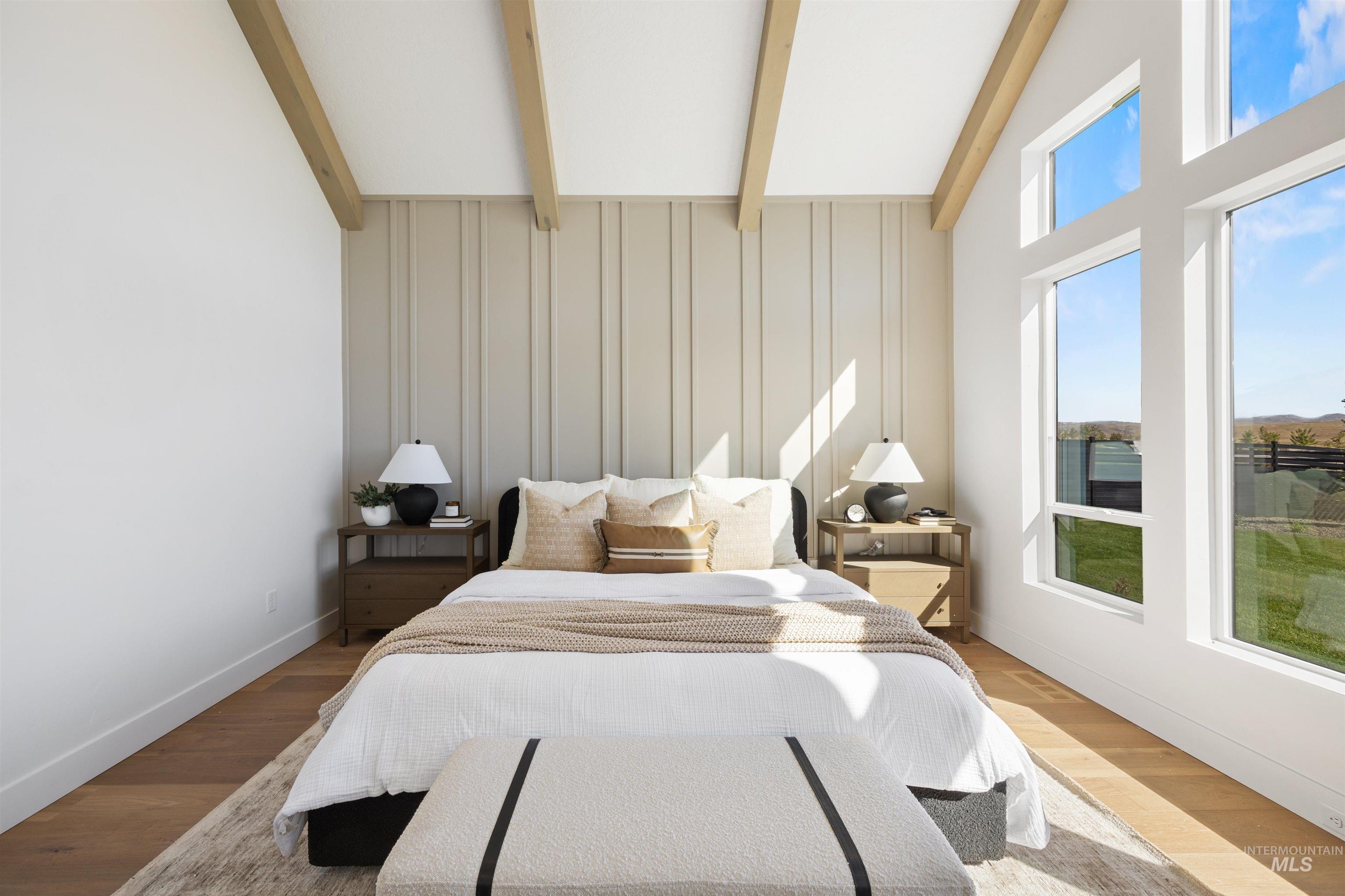 Bedroom featuring beamed ceiling, wood finished floors, and high vaulted ceiling