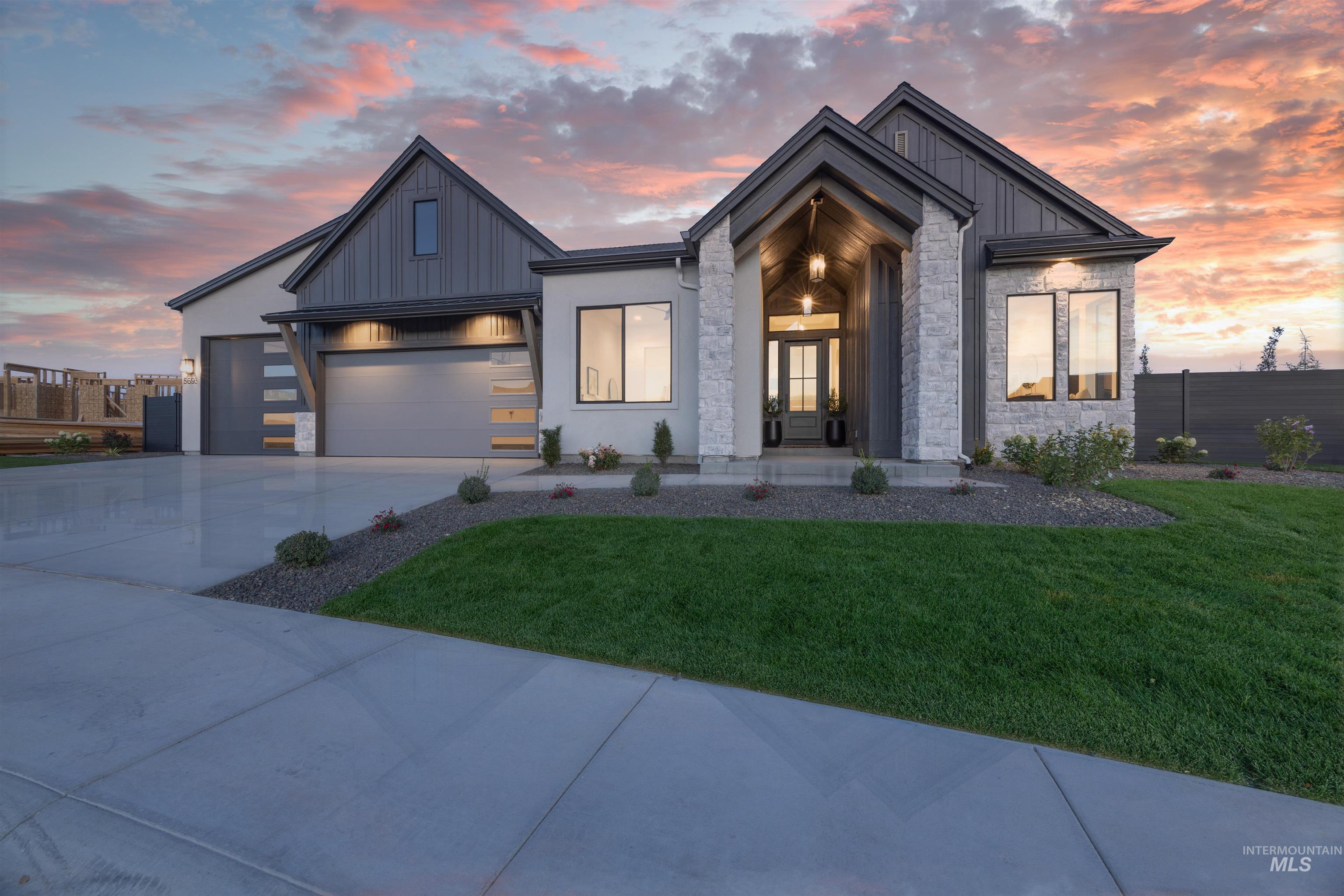 View of front of property featuring board and batten siding, driveway, stone siding, and a garage