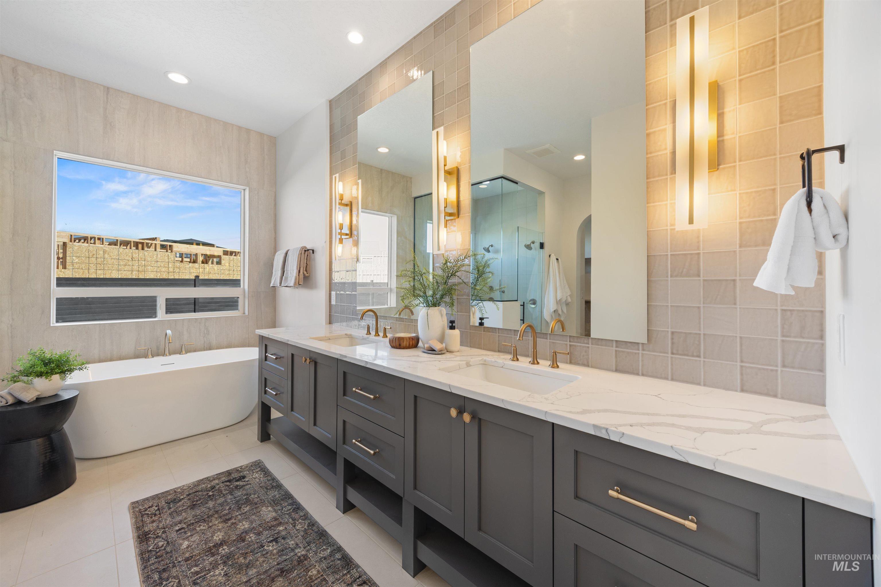 Full bath featuring double vanity, a freestanding bath, a shower stall, recessed lighting, and decorative backsplash