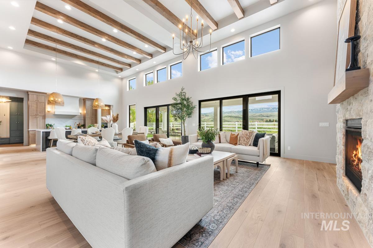 Living area with a stone fireplace, light wood-type flooring, and hanging lights
