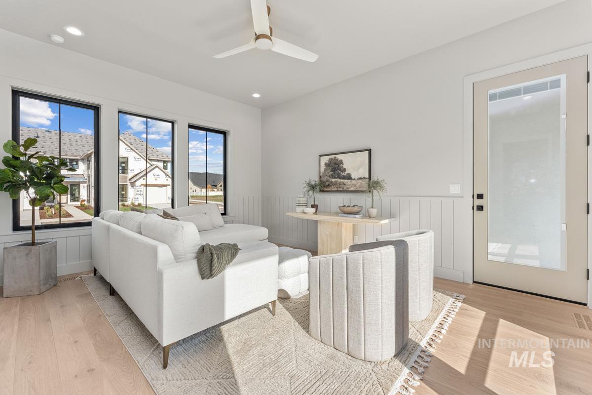Living area featuring a wainscoted wall, light wood-style flooring, a ceiling fan, and recessed lighting