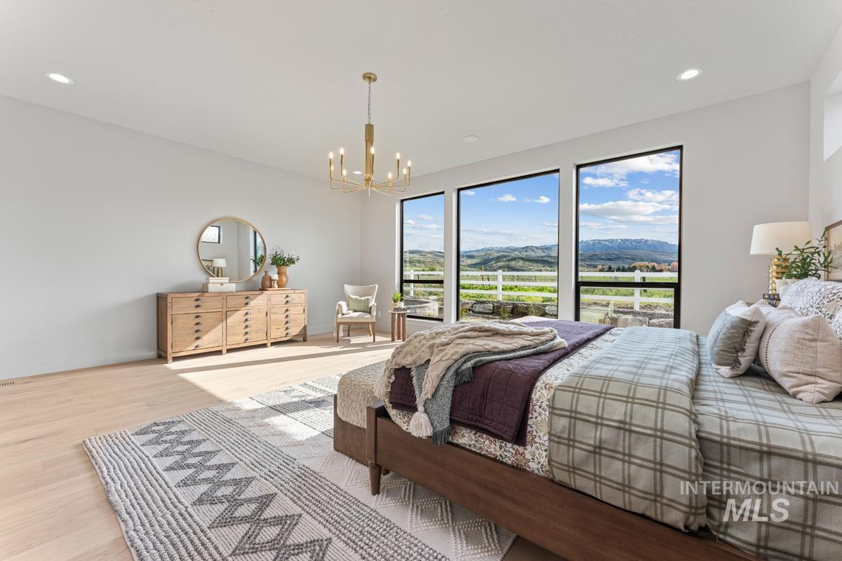 Expansive room featuring multiple floor-to-ceiling windows, light wood-finish flooring, recessed lighting, and a gold-tone chandelier