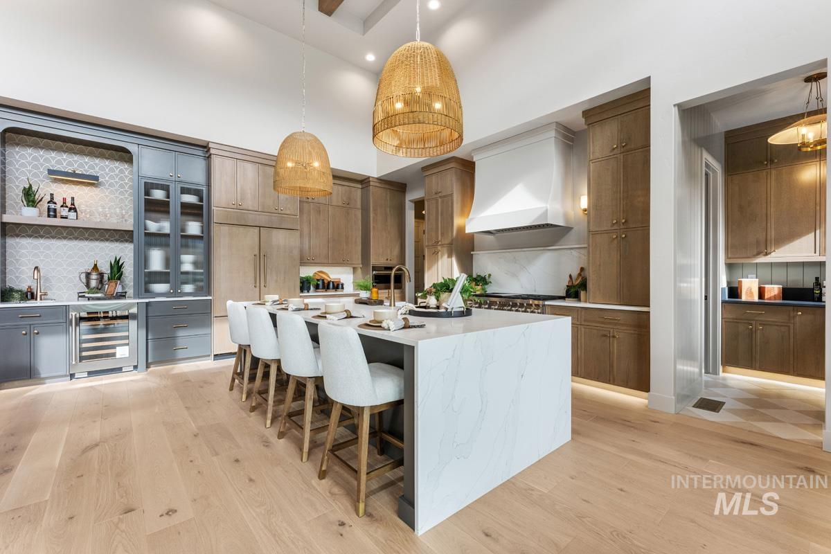 Two tone kitchen featuring open shelves, a high ceiling, light stone countertops, backsplash, and a large island