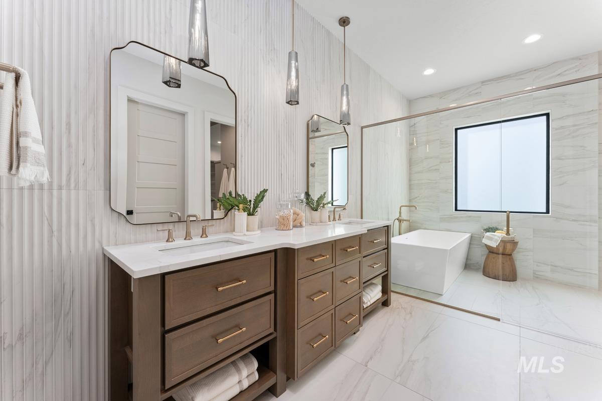 Full bathroom with double vanity, a freestanding tub, light marble finish floors, recessed lighting, and tile walls