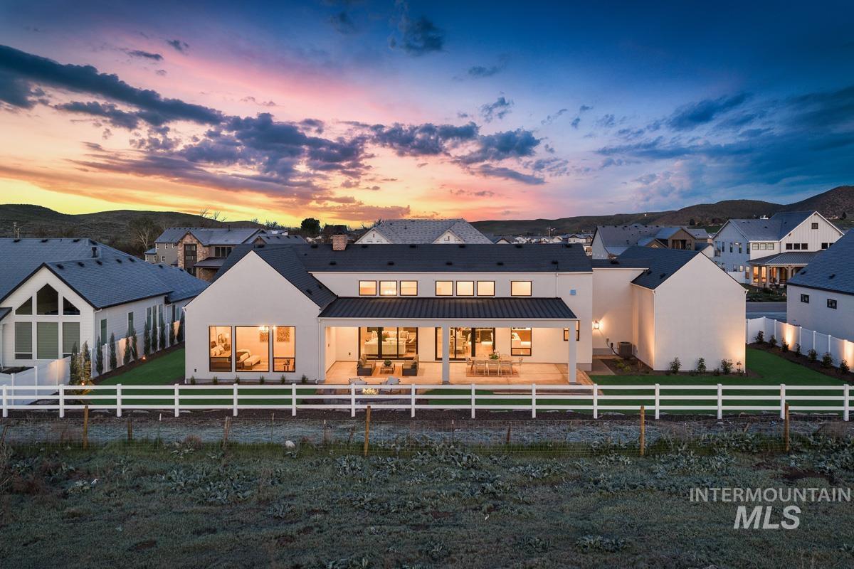 Back of house at dusk featuring a fenced backyard, a patio area, a standing seam roof, and an outdoor living space