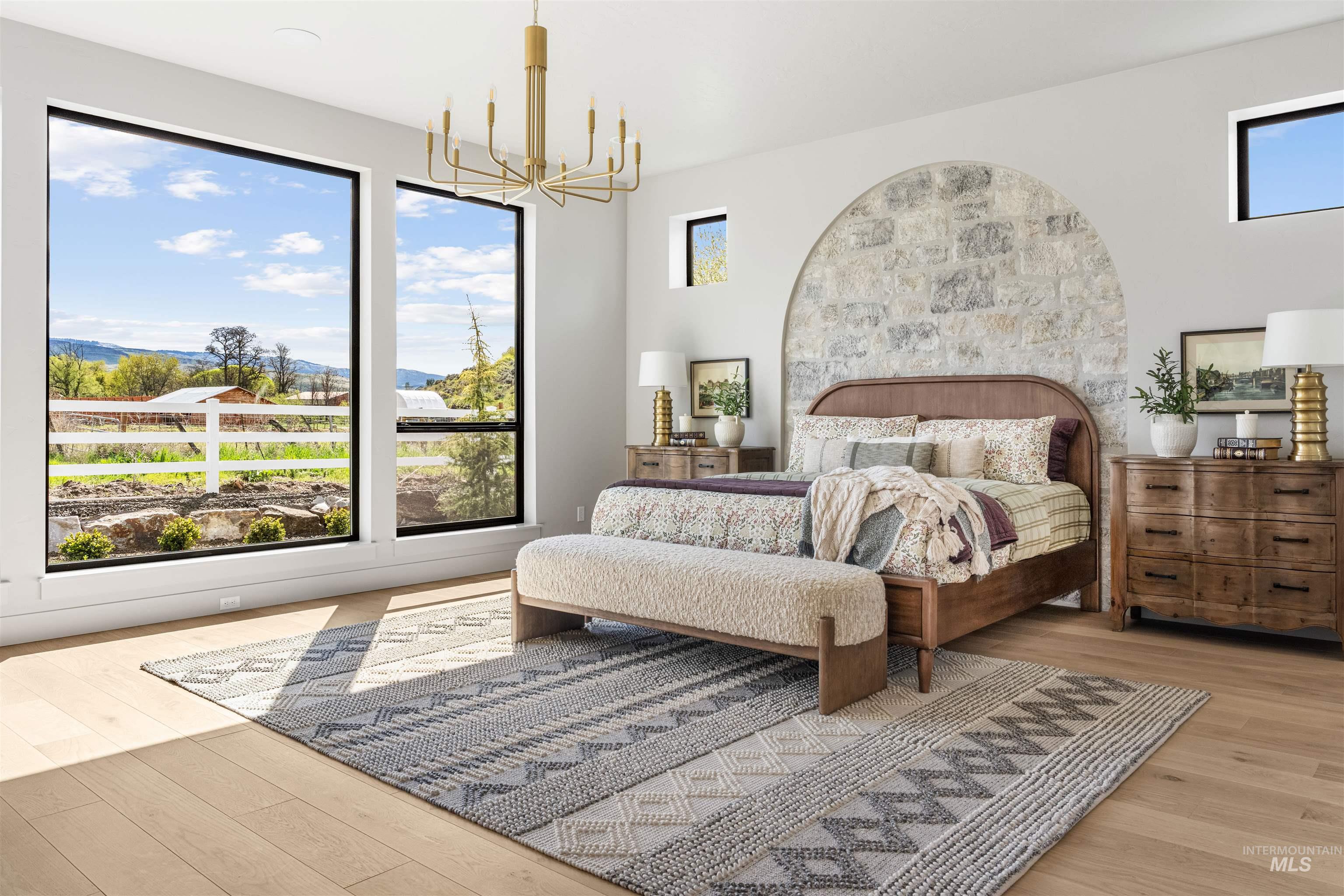 Bright interior with wide plank wood-finish flooring and an arched stone accent wall