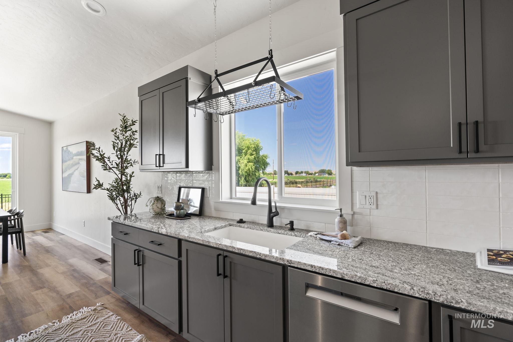 Kitchen with light stone countertops, dishwasher, light wood-style flooring, and tasteful backsplash