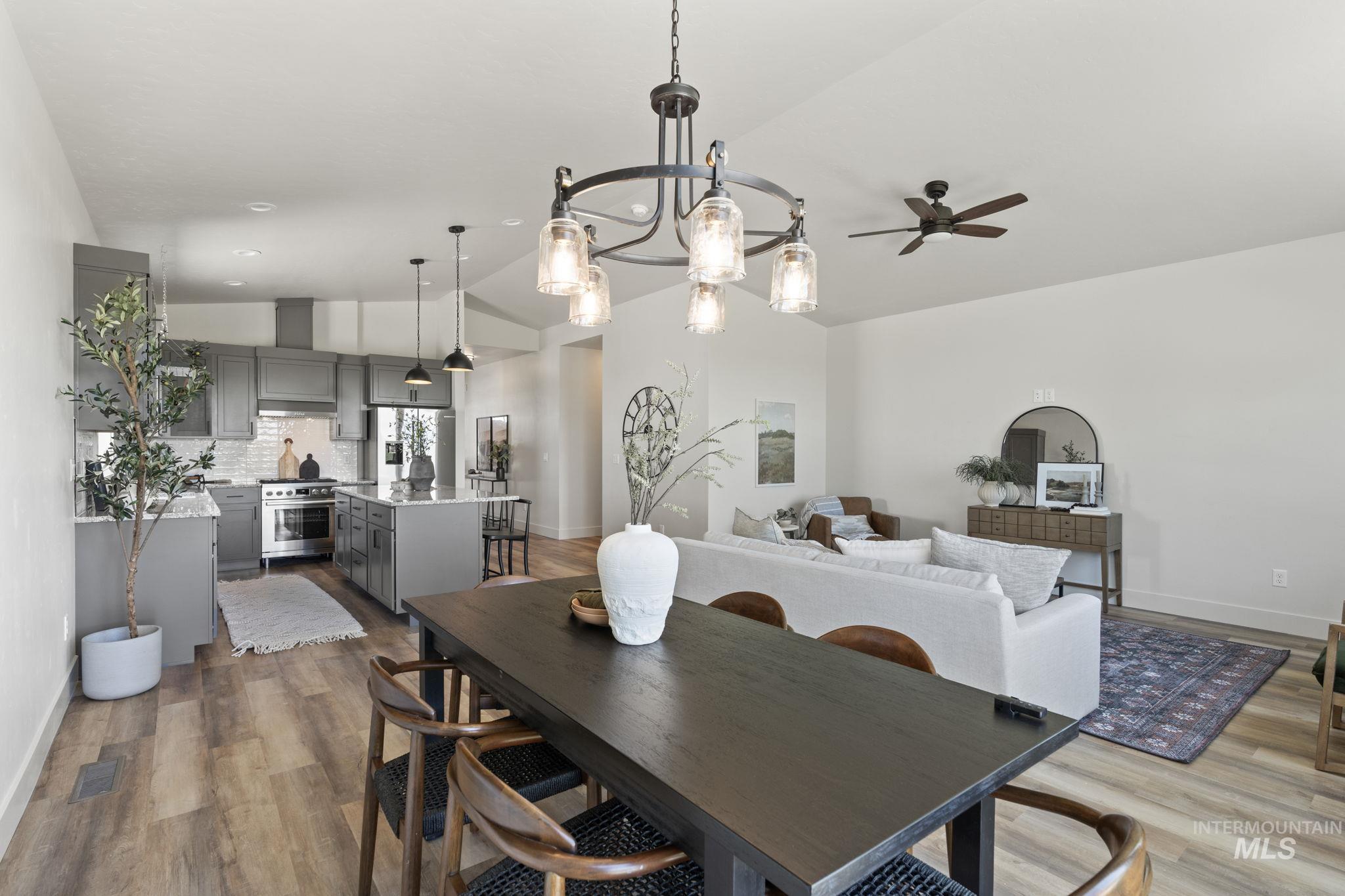 Dining space featuring vaulted ceiling, a chandelier, dark wood finished floors, and ceiling fan
