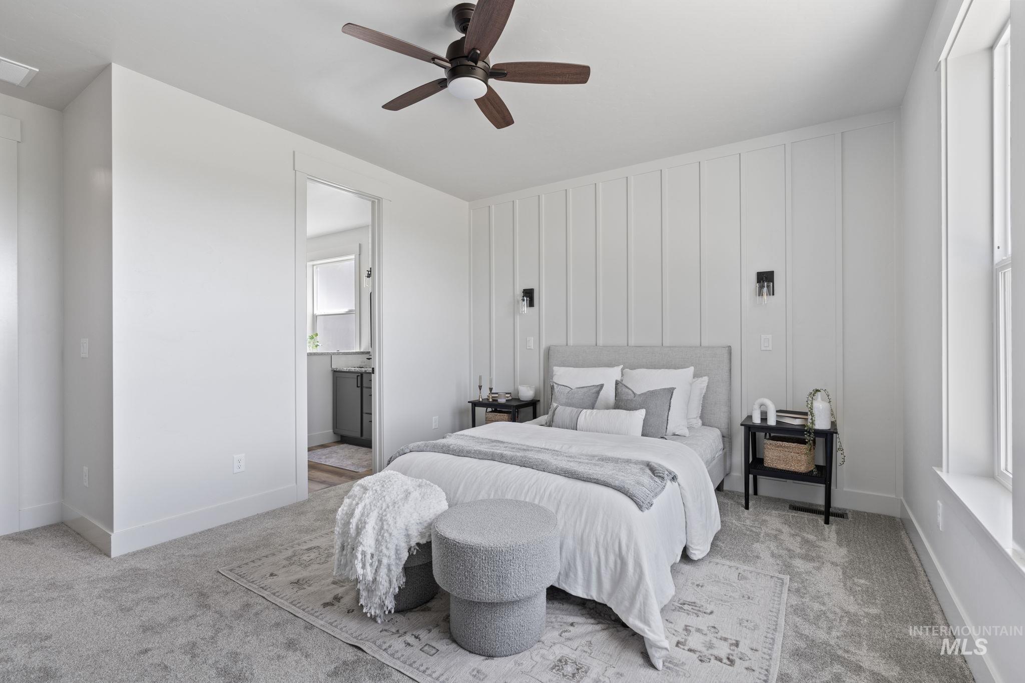 Bedroom with carpet flooring, ceiling fan, connected bathroom, and a decorative wall