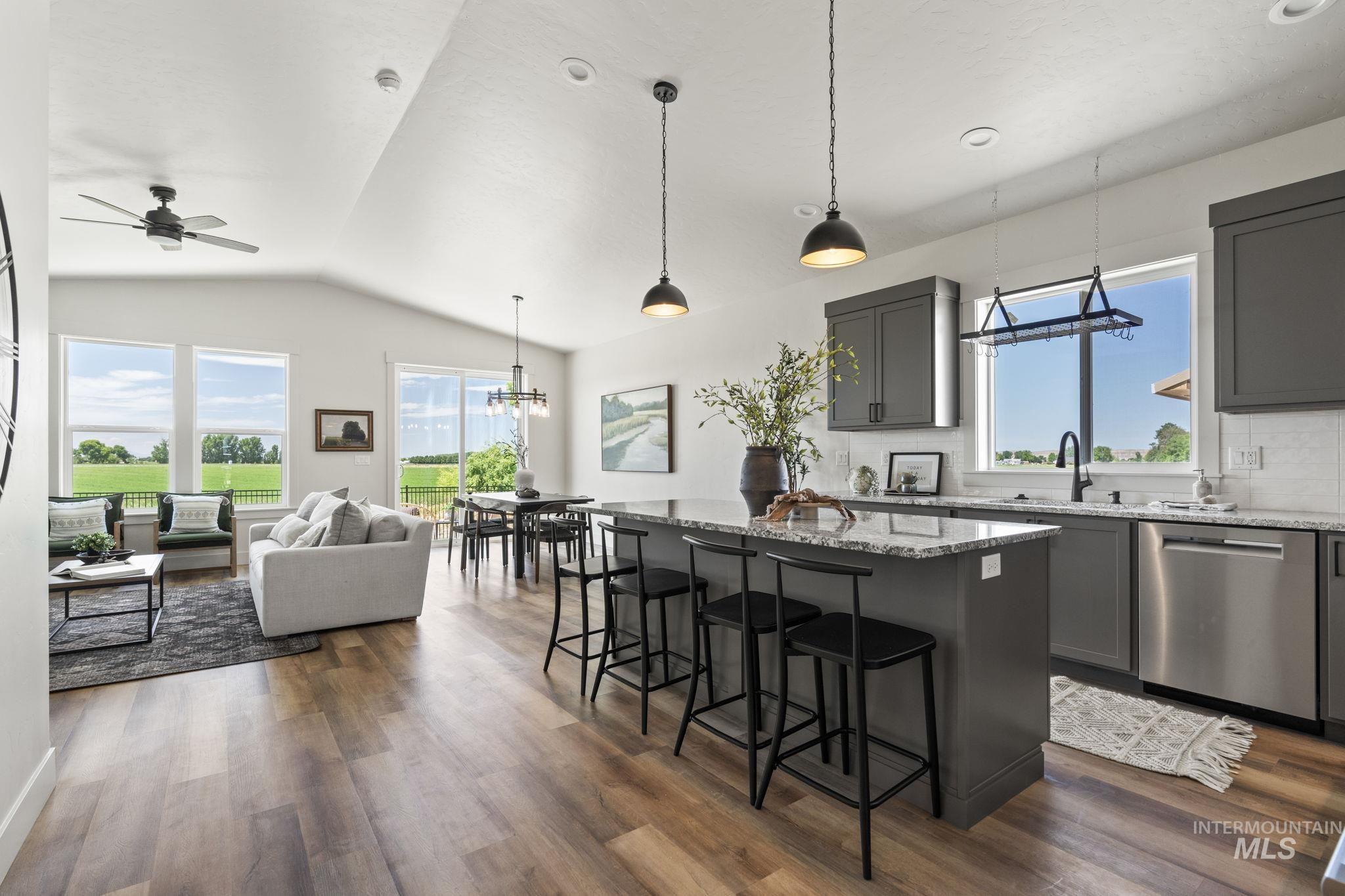Kitchen with light stone counters, a kitchen breakfast bar, a kitchen island, decorative backsplash, and plenty of natural light