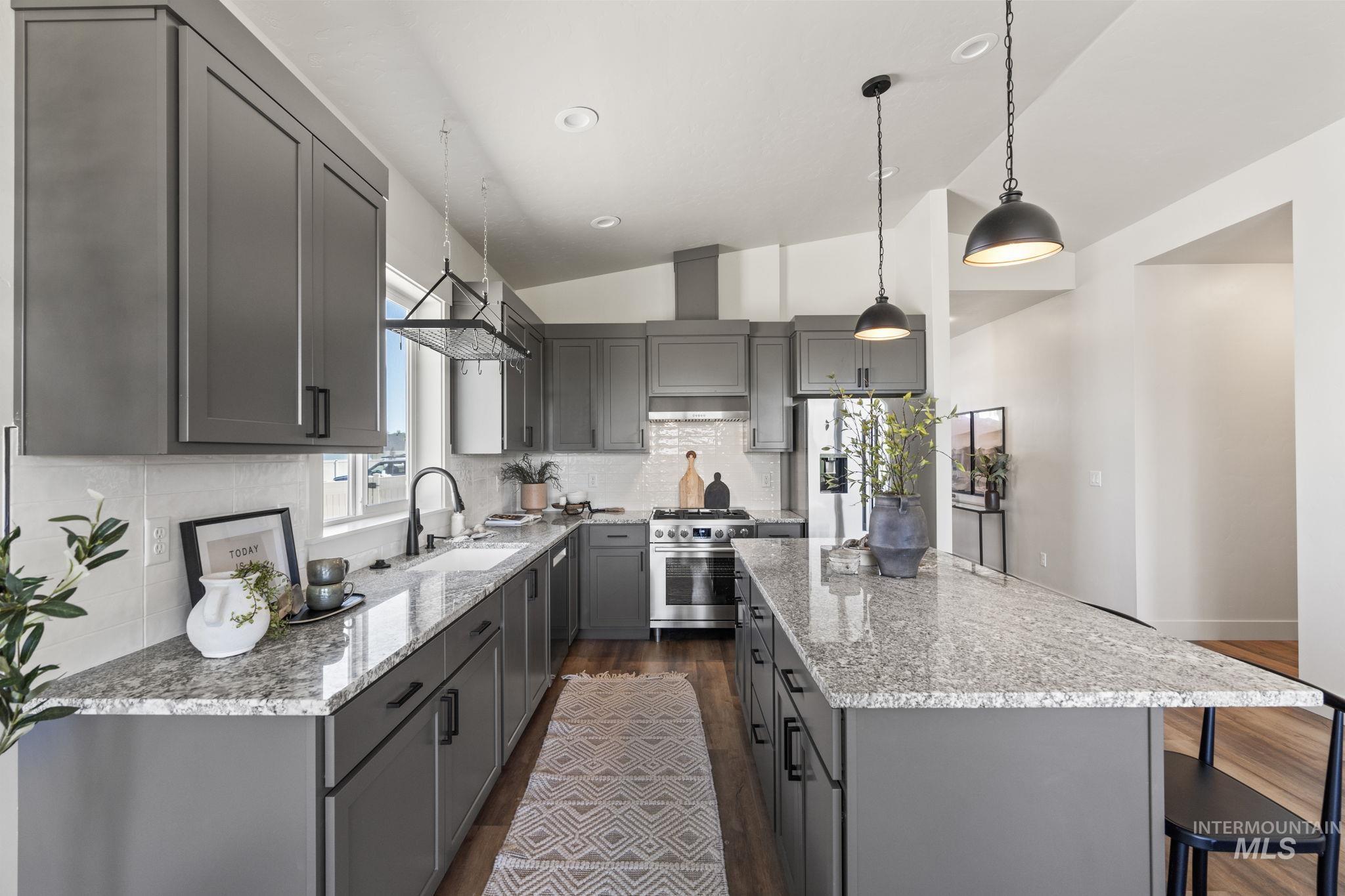 Kitchen featuring gray cabinets, vaulted ceiling, decorative backsplash, dark wood-style floors, and light stone countertops