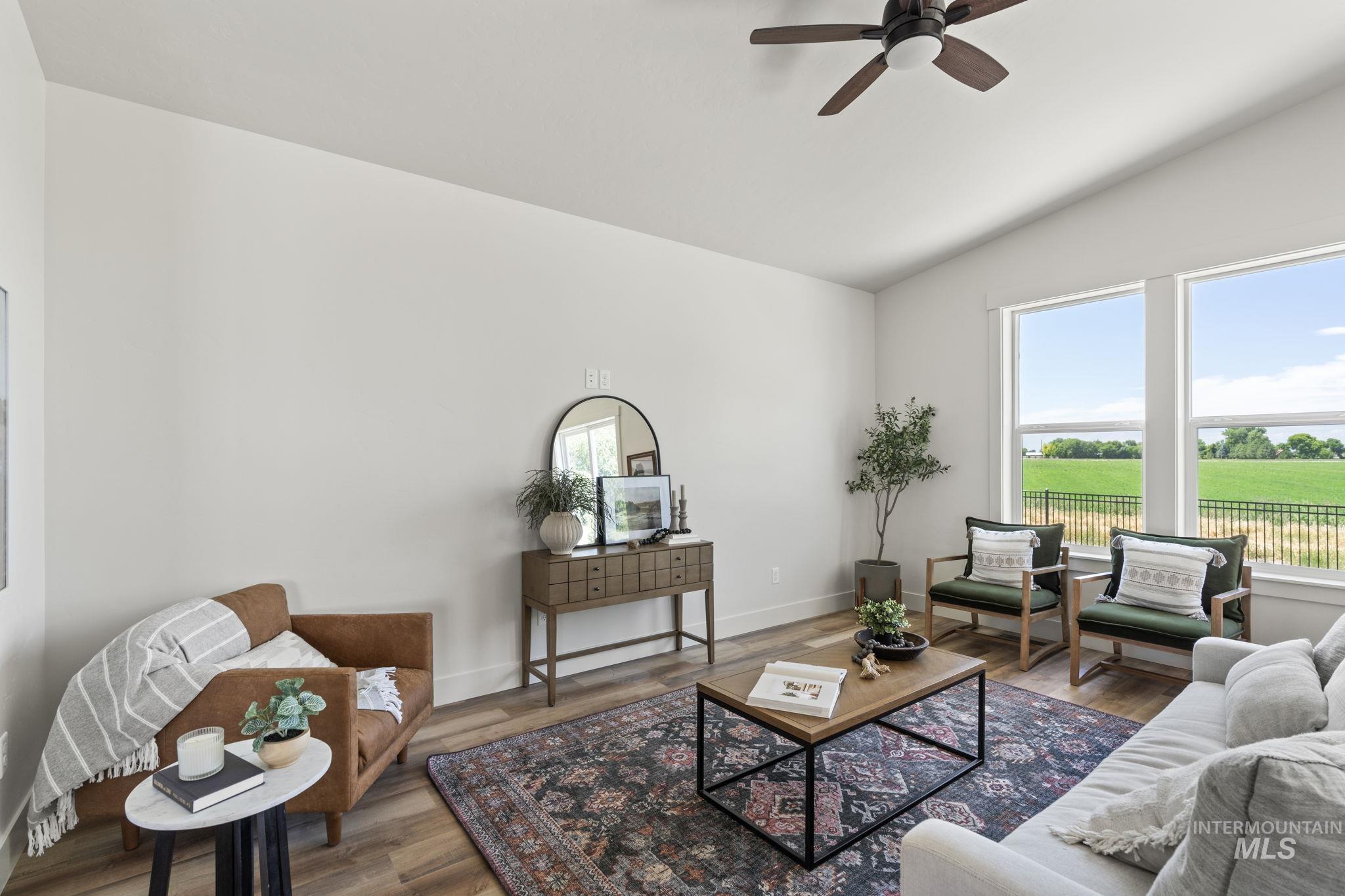 Living room featuring wood finished floors, vaulted ceiling, and ceiling fan