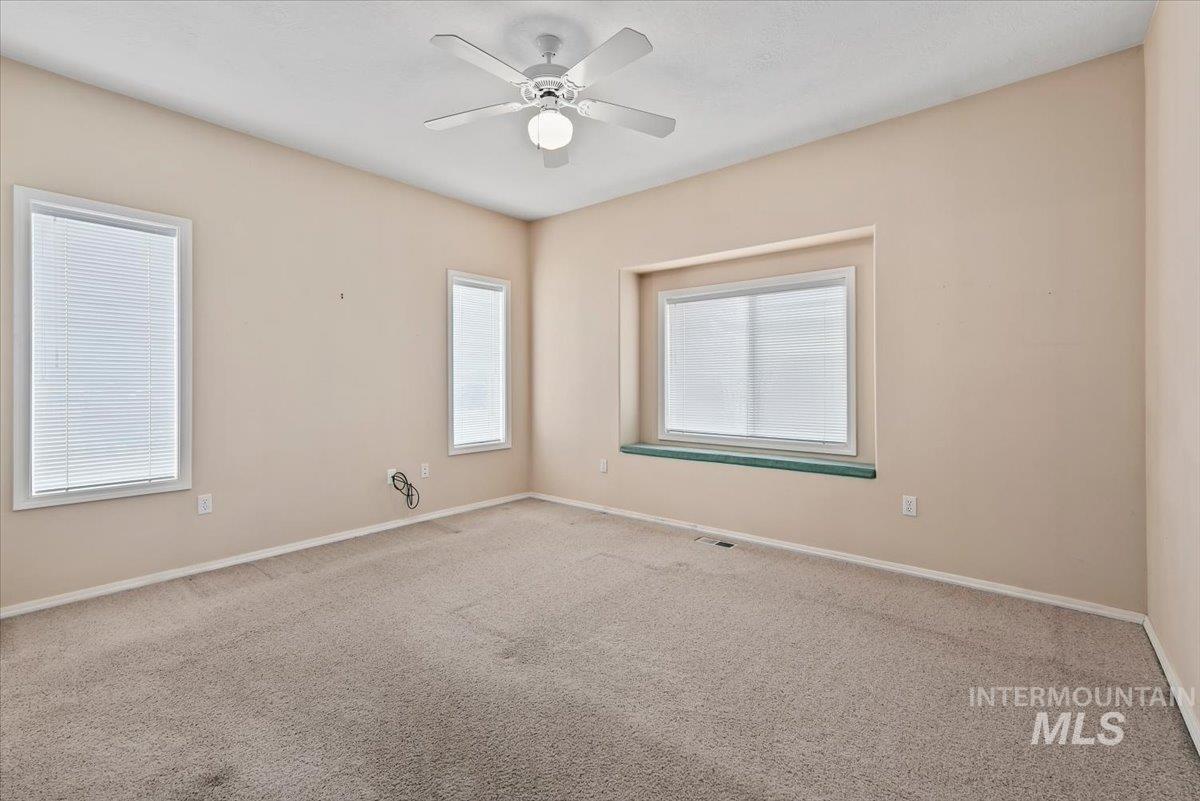 Carpeted spare room with baseboards and a ceiling fan