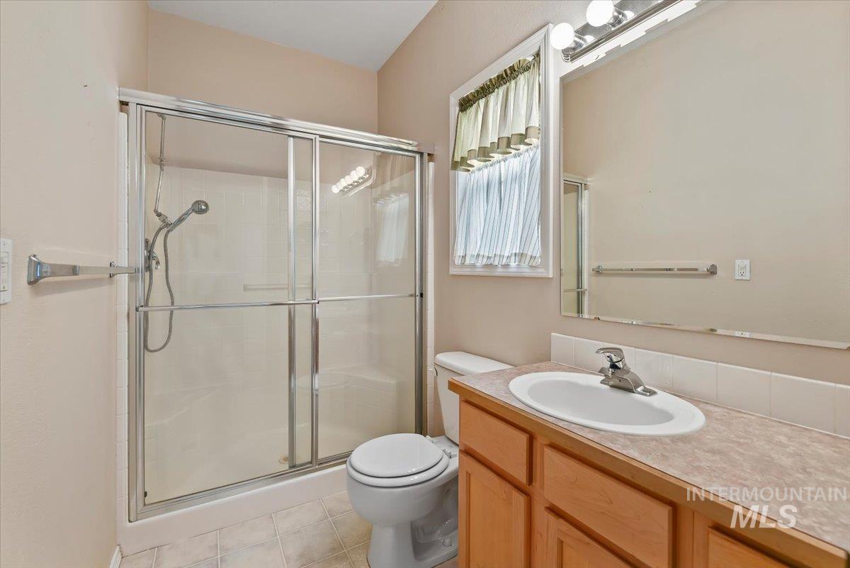 Full bath with vanity, a stall shower, and light tile patterned floors
