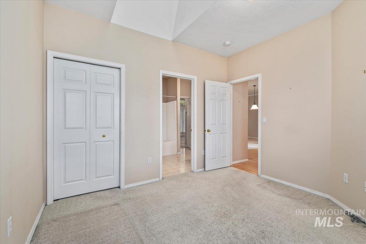 Unfurnished bedroom featuring light carpet, connected bathroom, and a closet