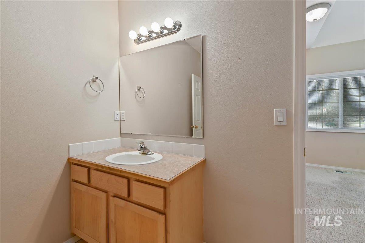 Bathroom with vanity, a textured wall, and carpet